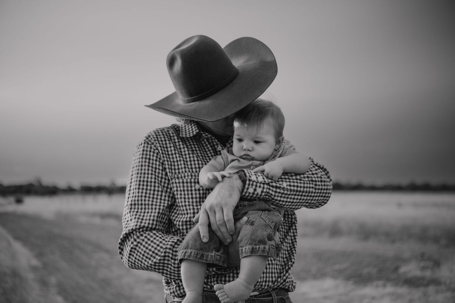 Black and white family moment captured in rustic country setting.