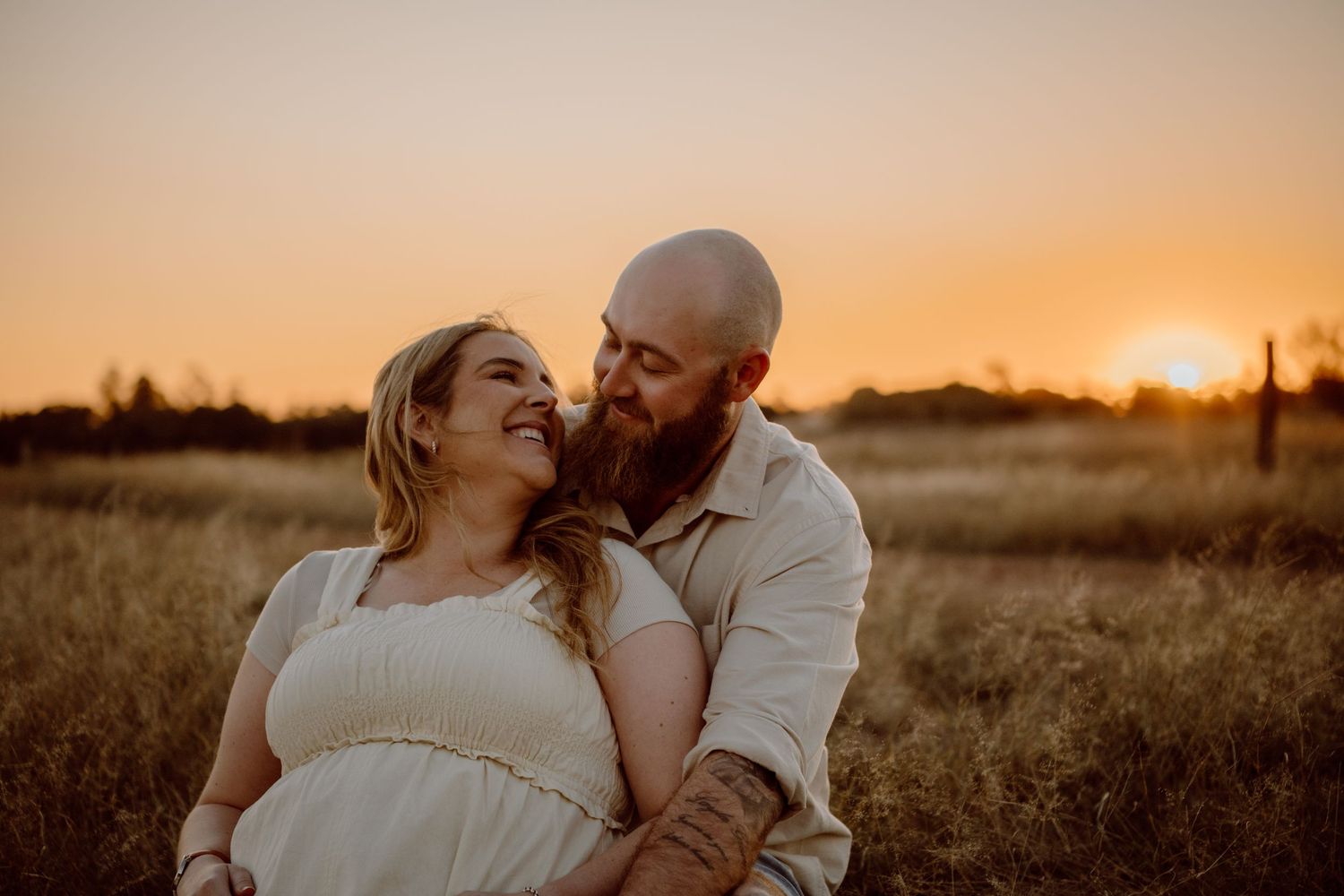 A romantic sunset moment captured in a rural field with warm golden light.