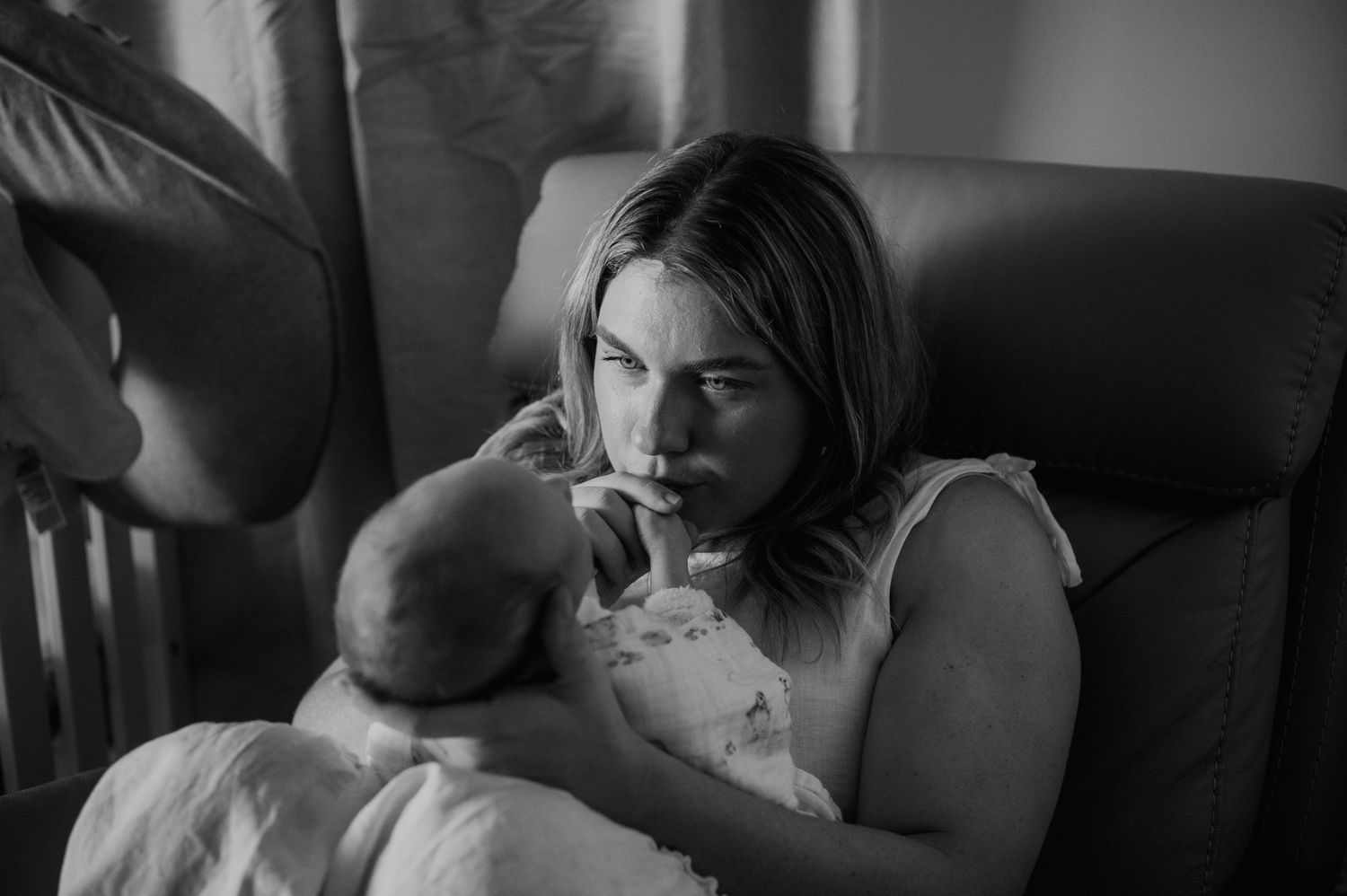 A tender black and white photograph showing a parent feeding a baby in a peaceful intimate moment.