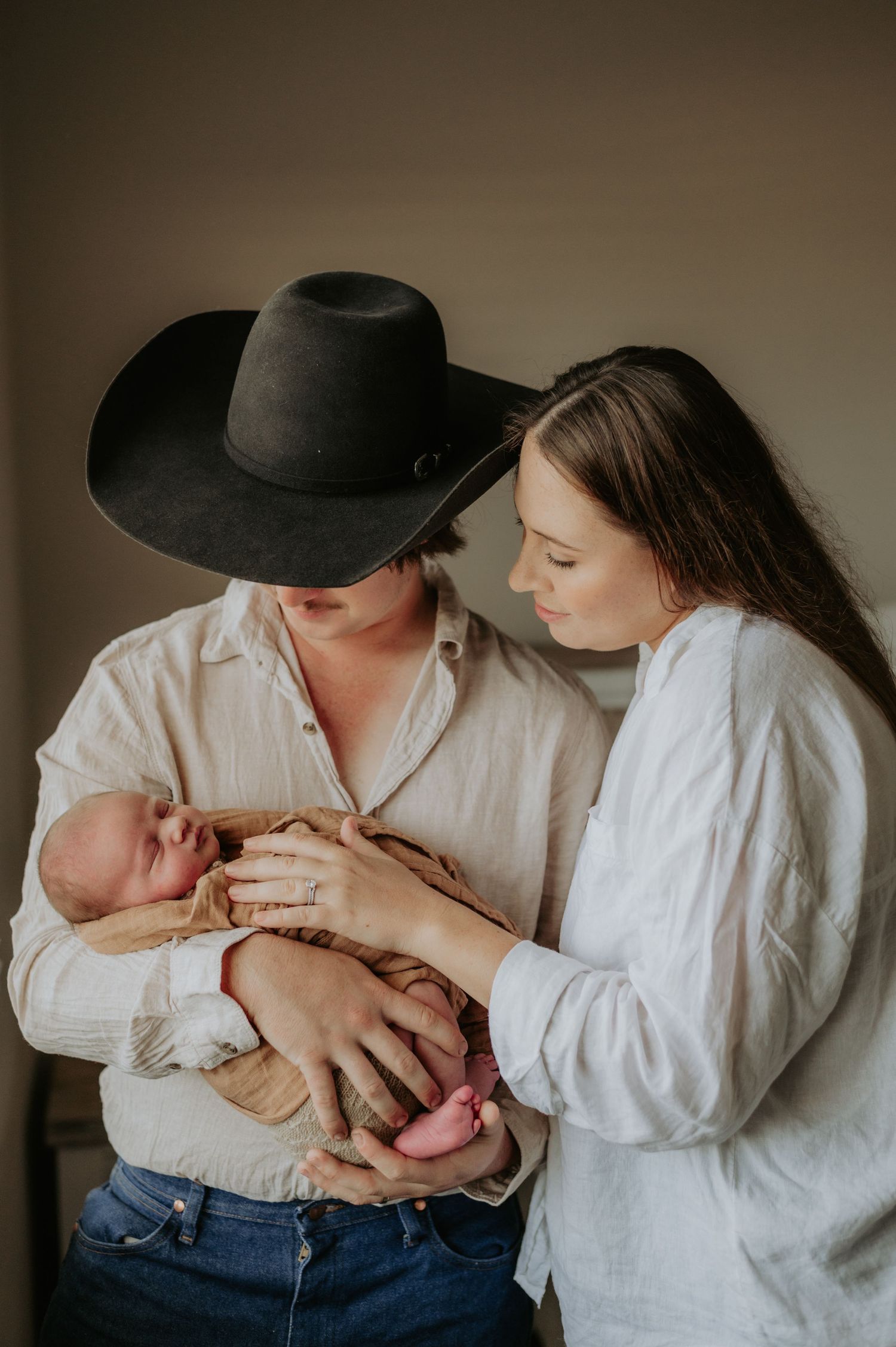 Rustic family photoshoot featuring white clothing and wide-brimmed hat in warm tones.