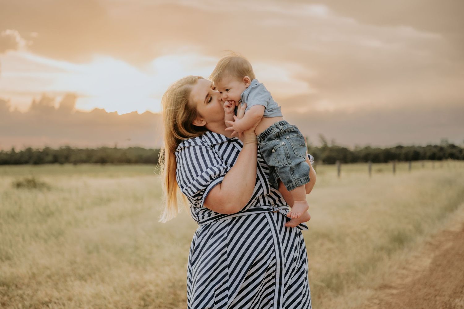 A tender moment captured between parent and child in a sun-drenched field at golden hour.