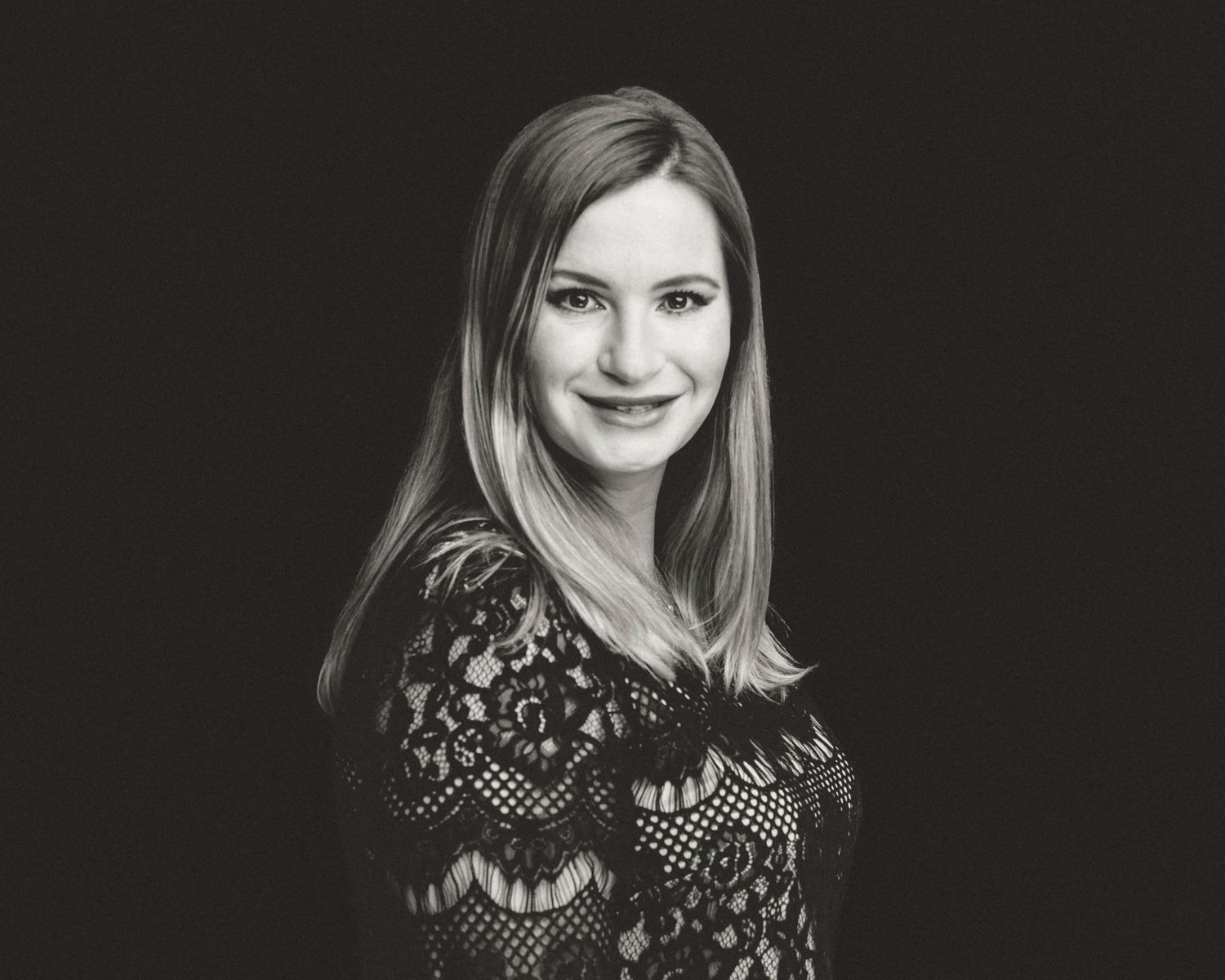 A black and white studio portrait against dark background with soft lighting.