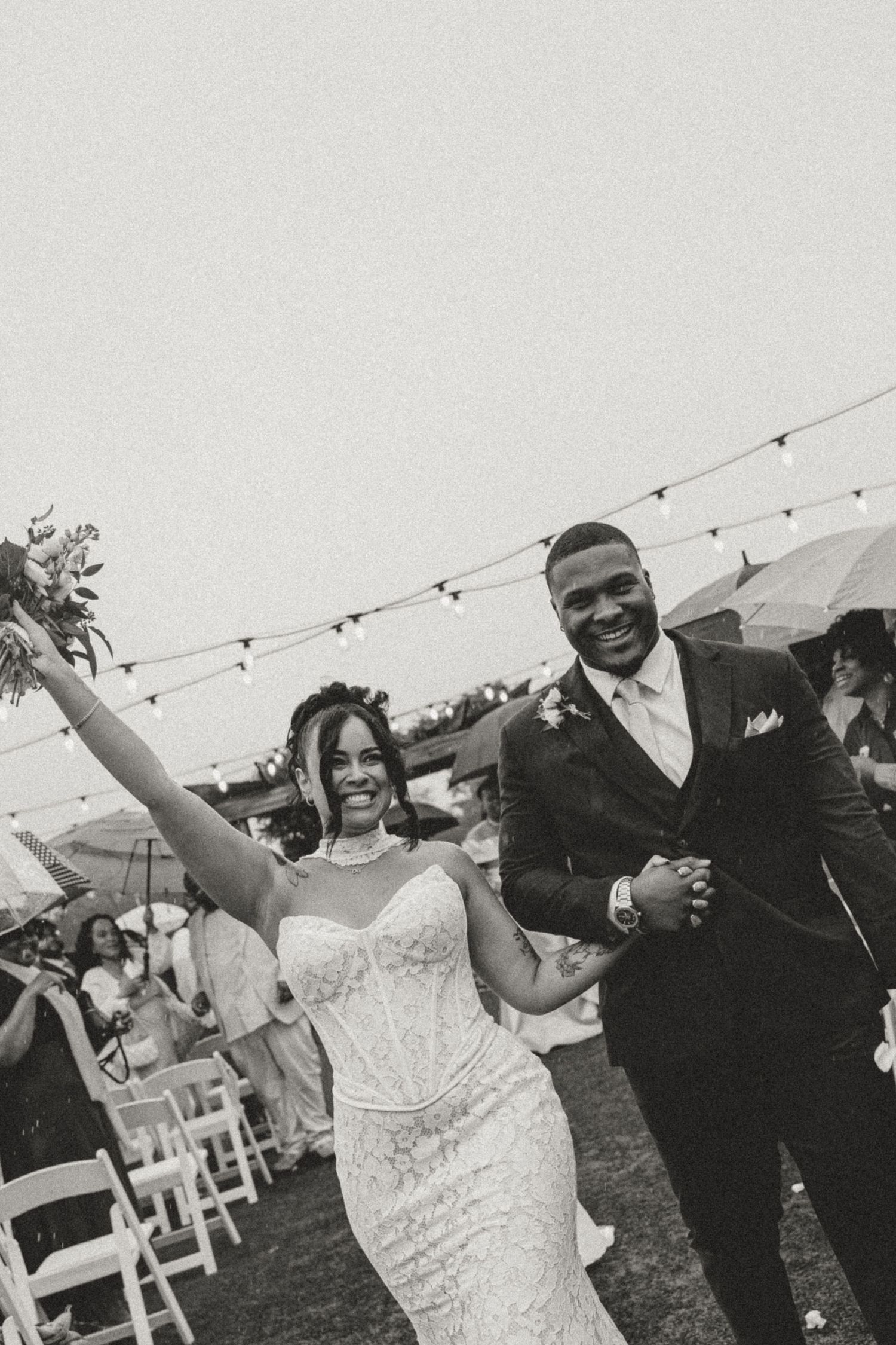 Black and white photo of a joyful bride and groom walking down the aisle after their outdoor wedding ceremony.
