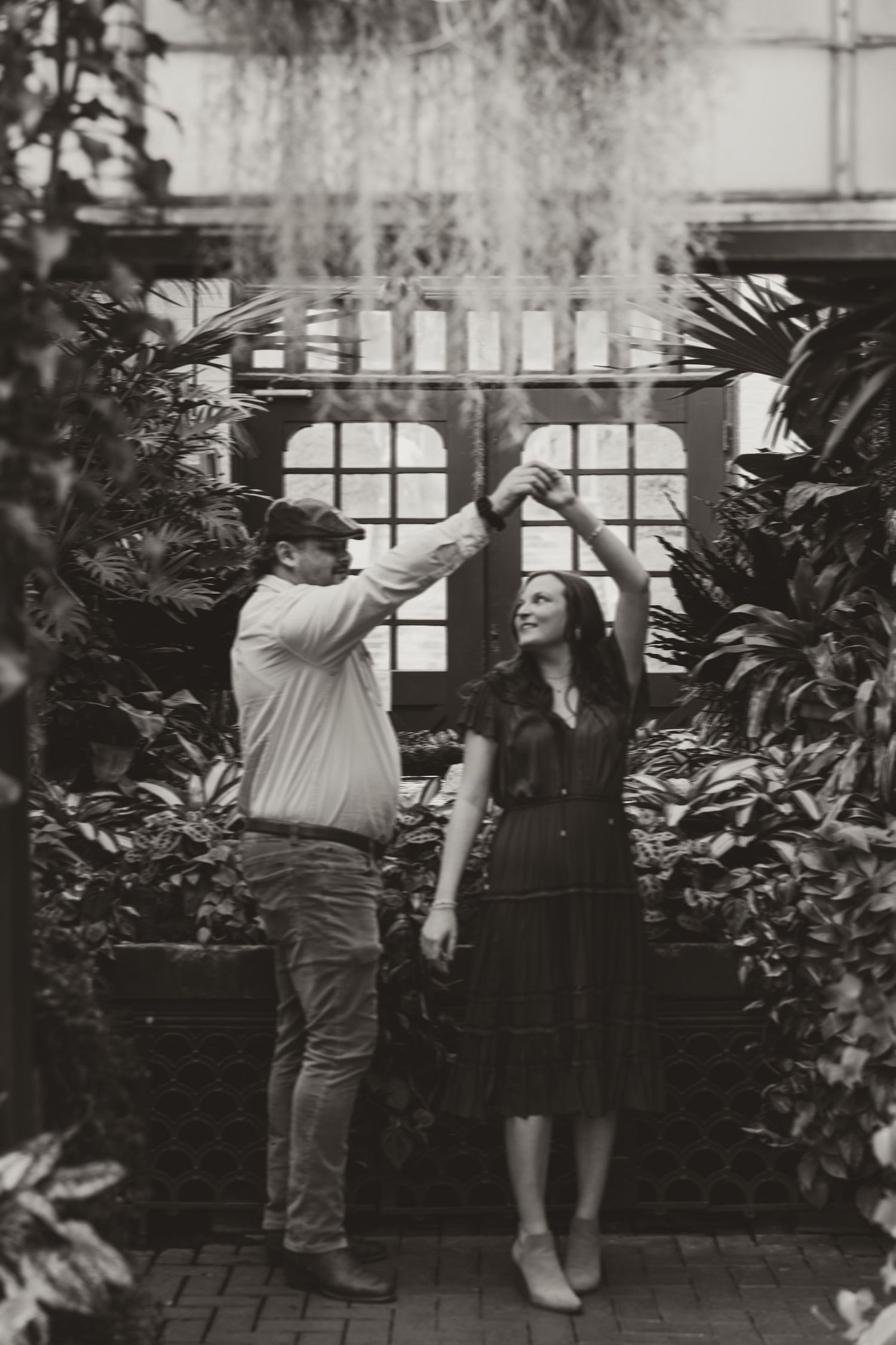 Black and white sequence showing two people dancing together in a greenhouse or conservatory setting.