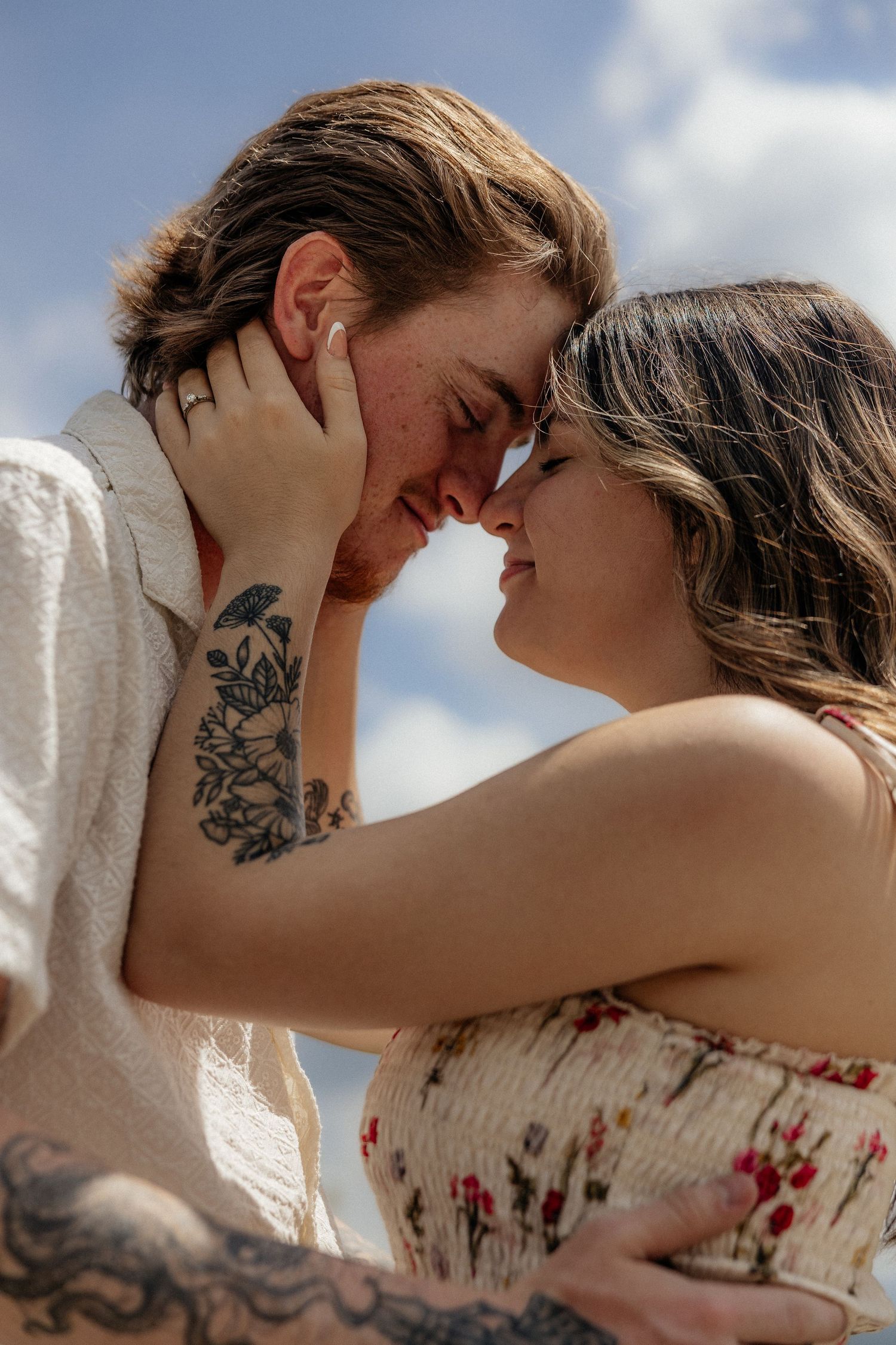 A romantic couple embraces intimately against a bright sunlit background, creating a tender silhouetted moment.