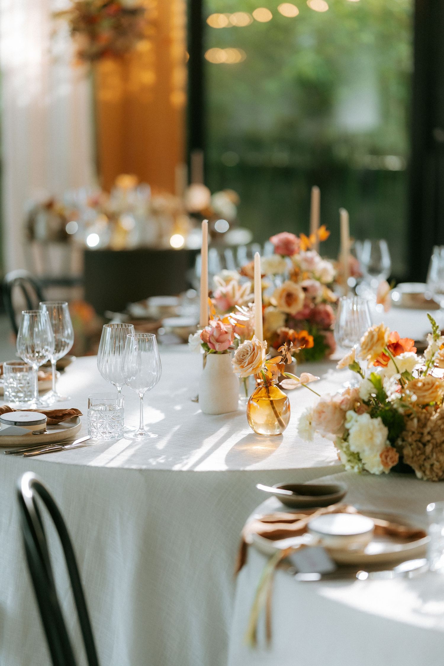 Elegant wedding reception table set with crystal glassware, candles, and colorful floral centerpieces.
