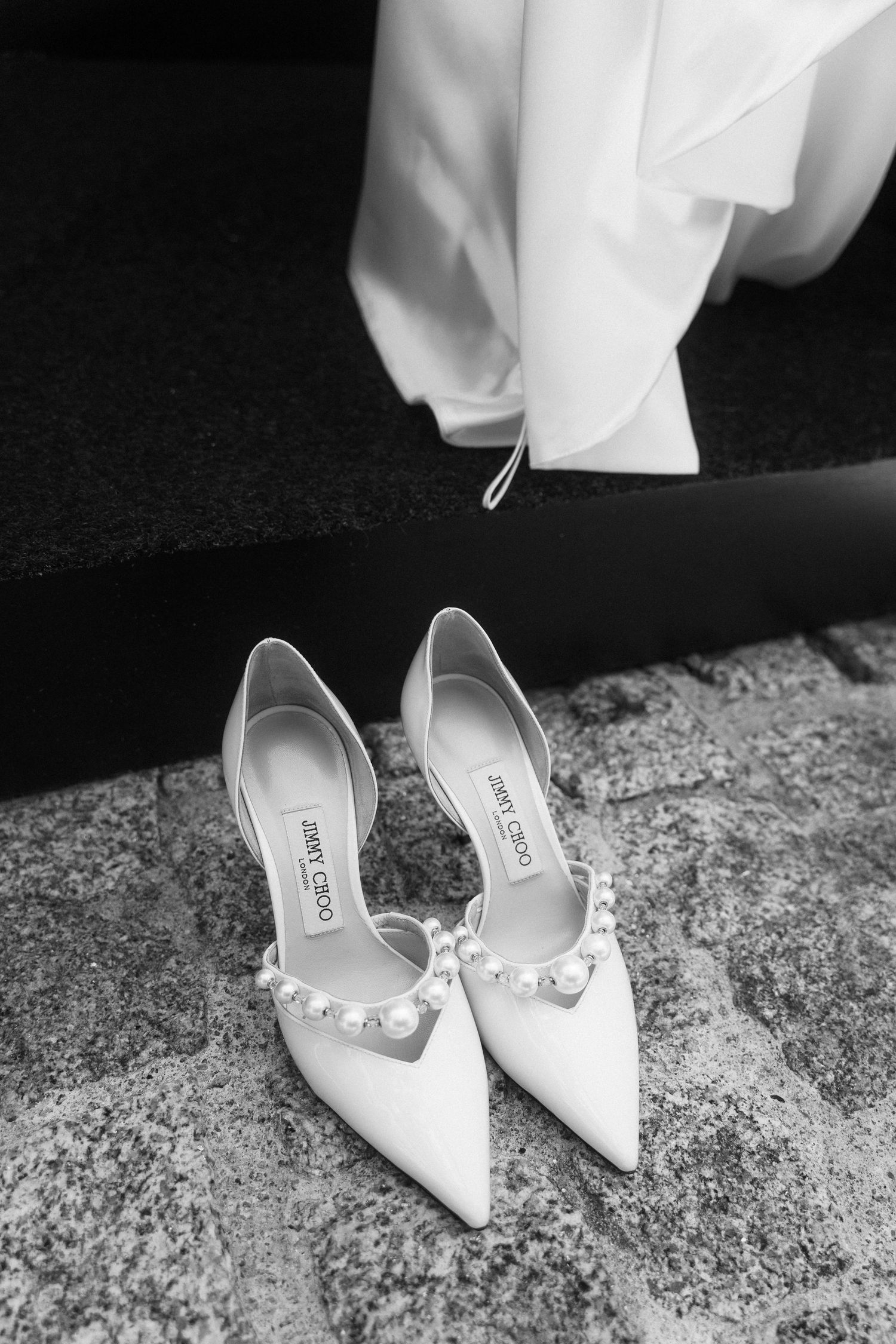 Black and white photo of Jimmy Choo pearl-embellished bridal heels on stone steps.