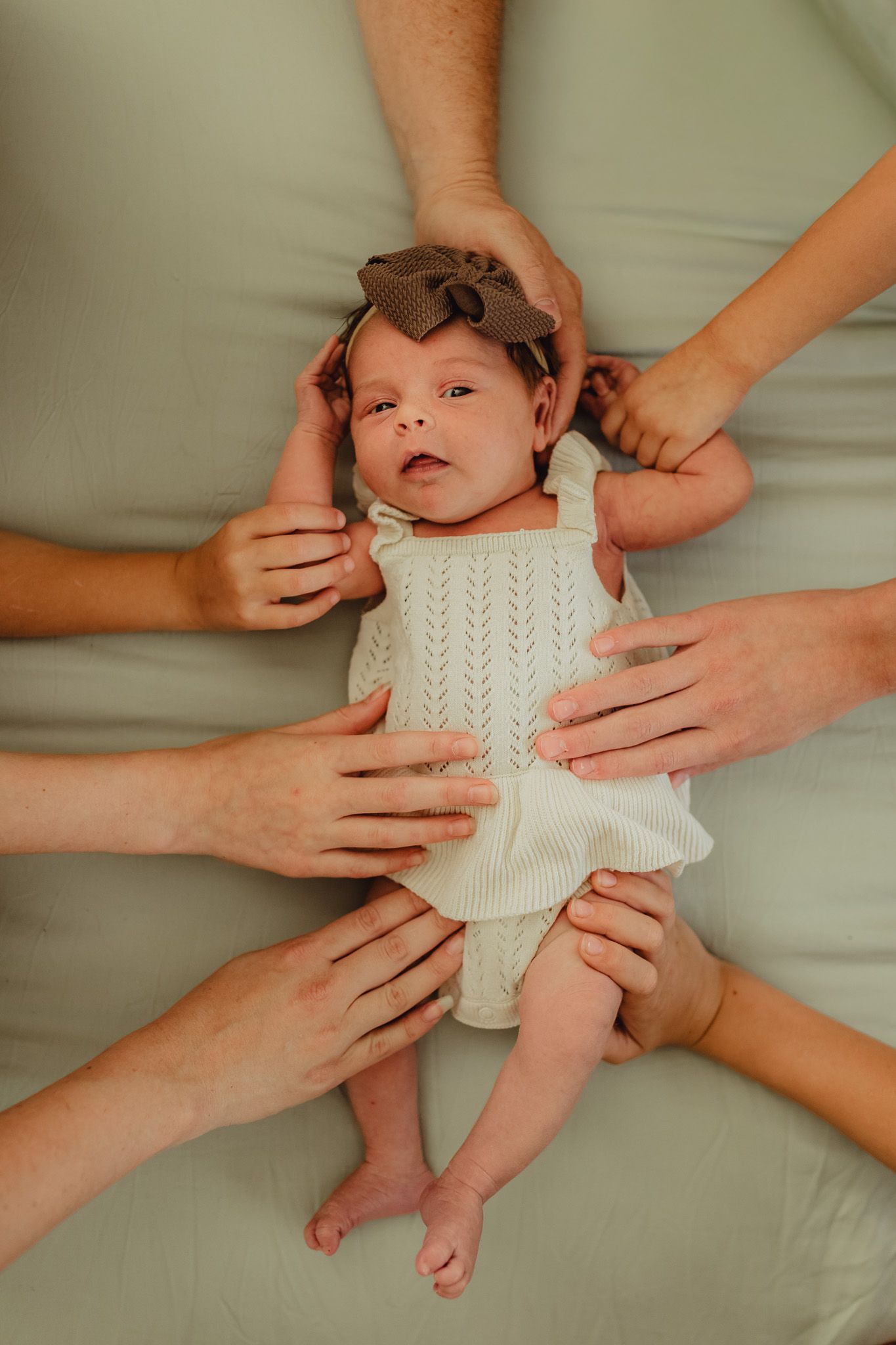 Bradenton in-home newborn photography featuring parents cuddling their newborn in a cozy lifestyle session. big family, all hands on baby