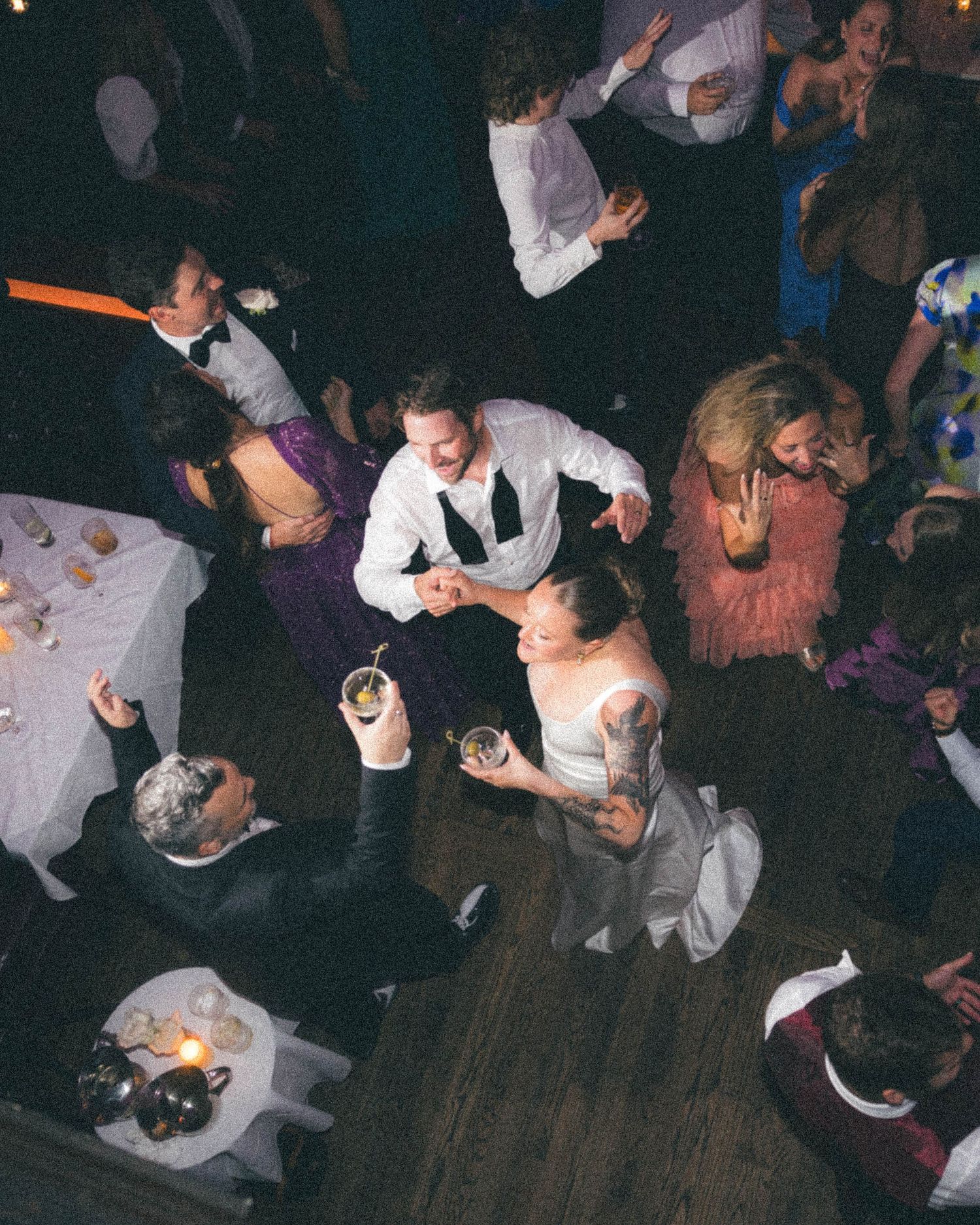 Aerial view of wedding guests dancing and celebrating on wooden dance floor.