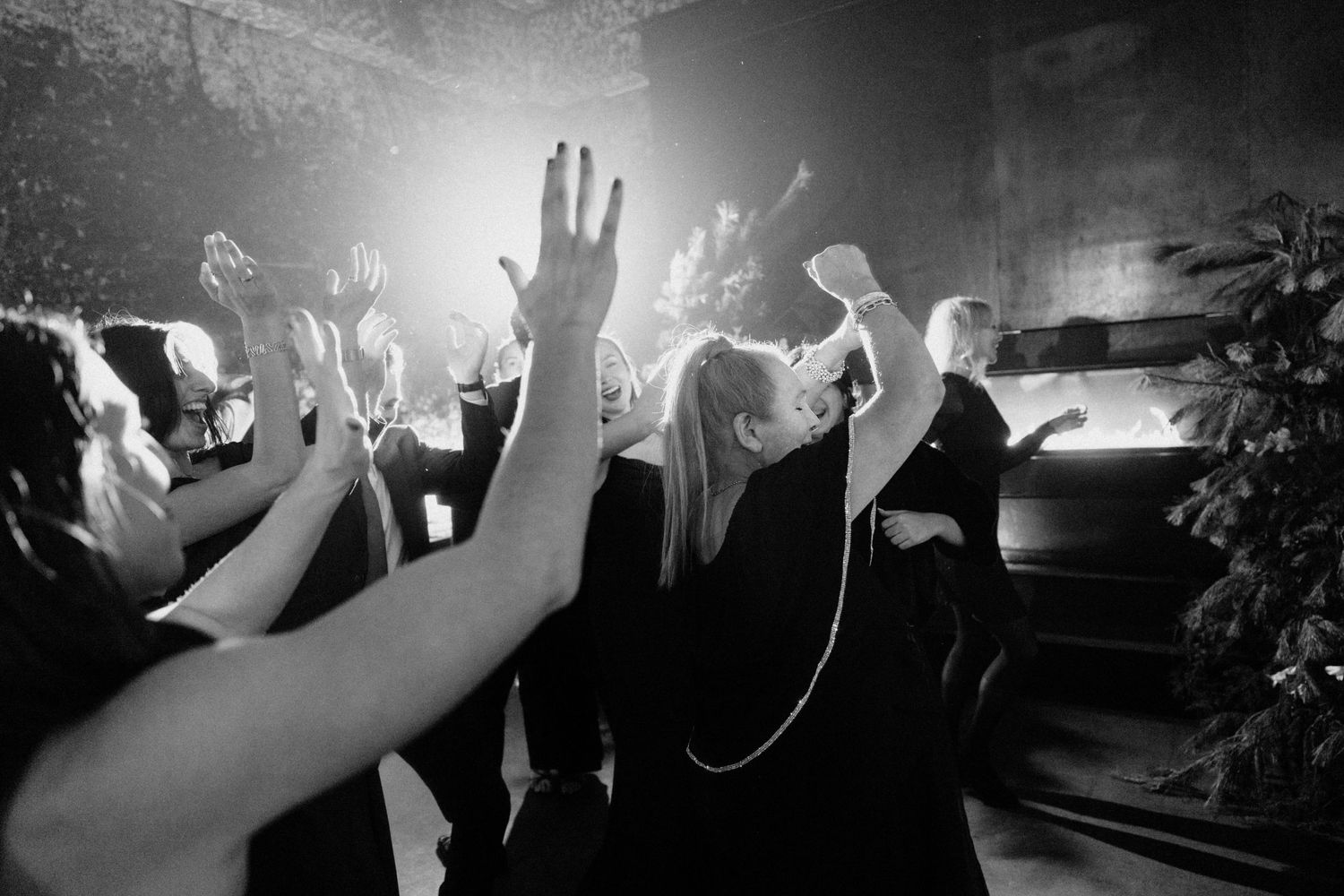 Guests dancing with hands raised at a lively black and white wedding reception party.