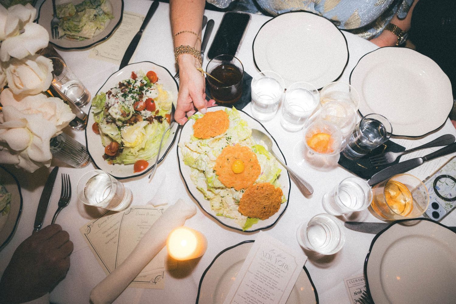 Overhead view of wedding reception dinner table with colorful salads, candles, and place settings.