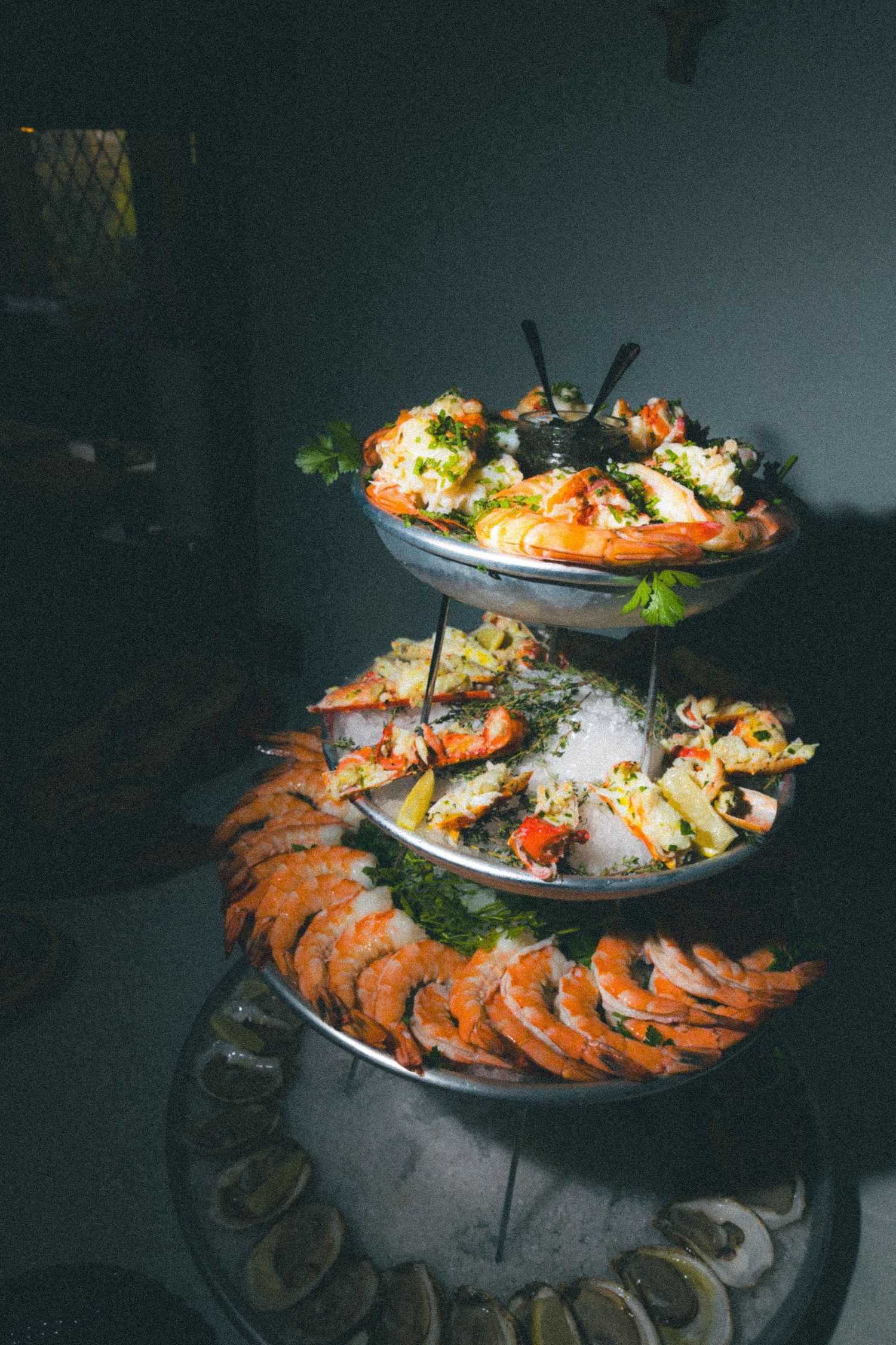 Three-tiered seafood tower display with shrimp, crab, and oysters on ice at wedding reception.
