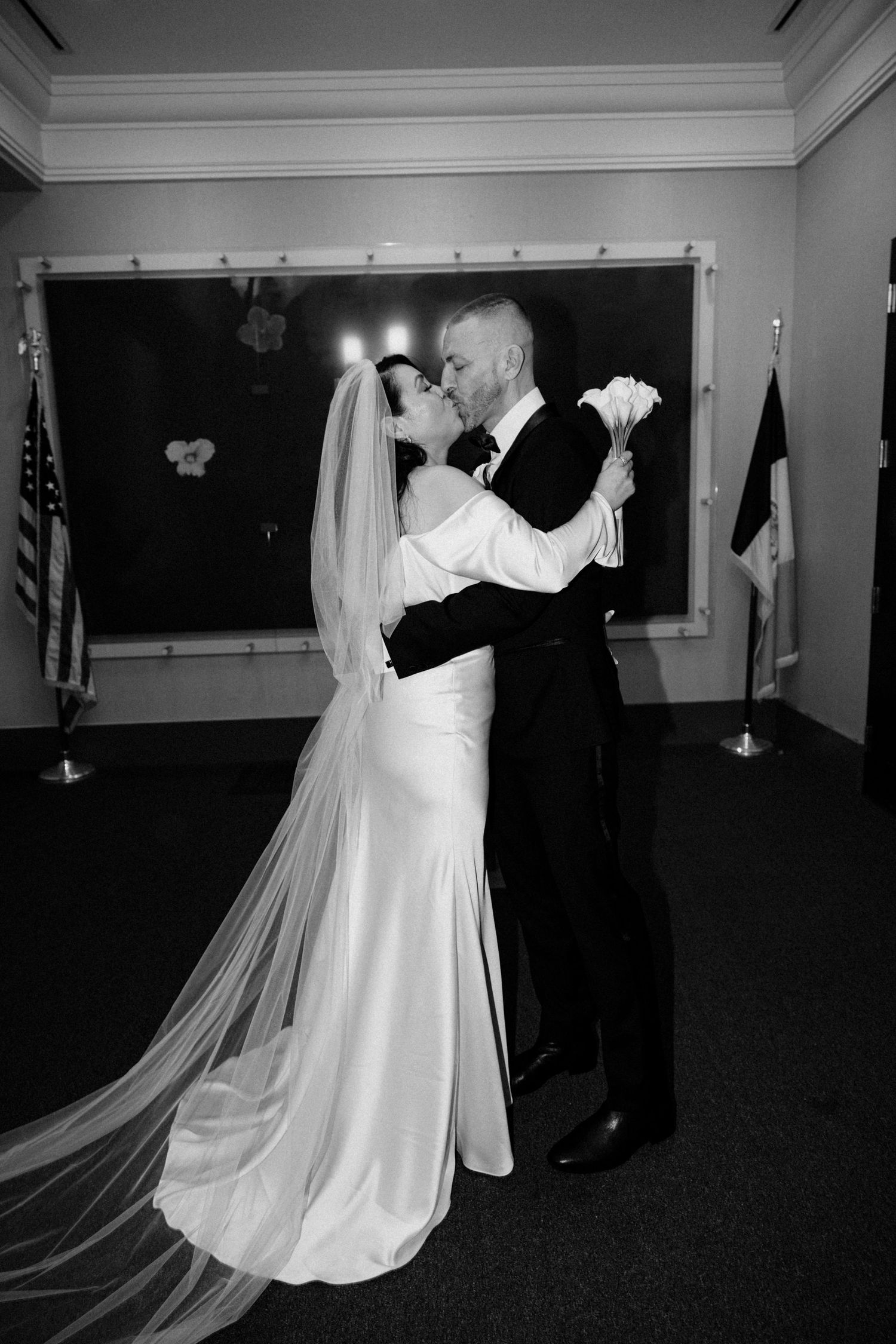 Bride and groom share a first kiss during their wedding ceremony in black and white.