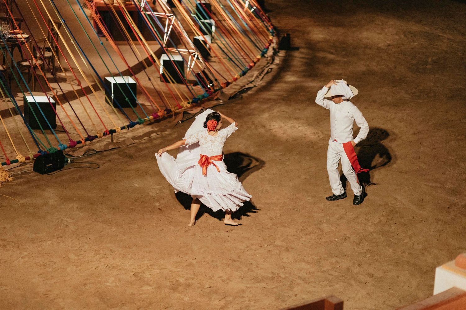 Traditional Mexican folk dancers in white costumes performing at a wedding celebration venue.