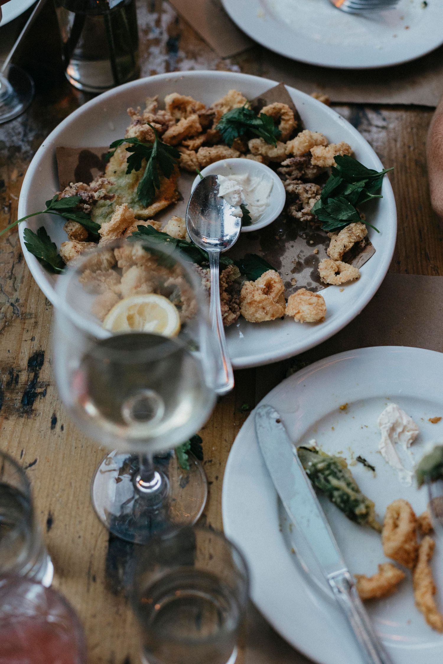 Plate of crispy fried calamari with herbs and lemon served with white wine at wedding reception dinner.