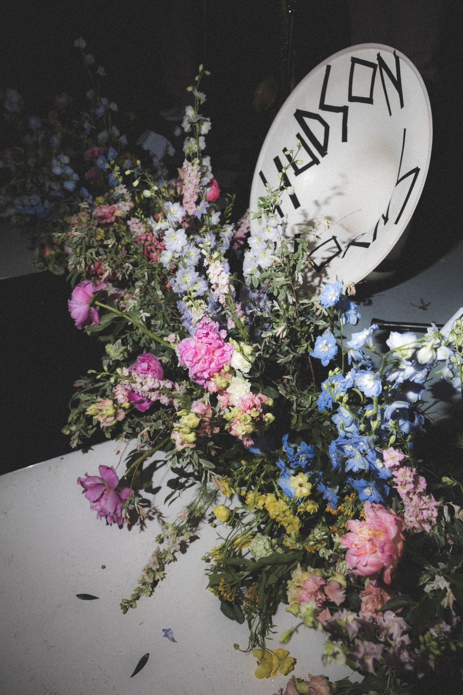 Colorful floral arrangement with pink, blue, and yellow flowers beside a Hudson sign.