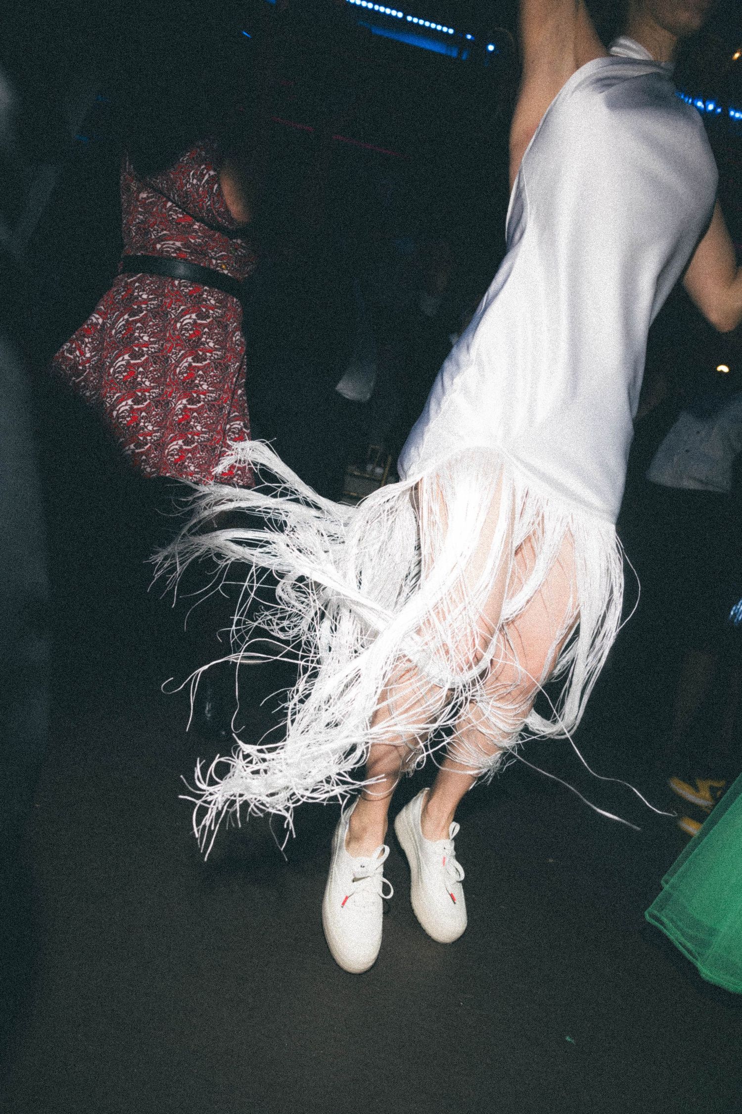Close-up of bride's white feathered wedding dress hem swirling during energetic dance at reception.