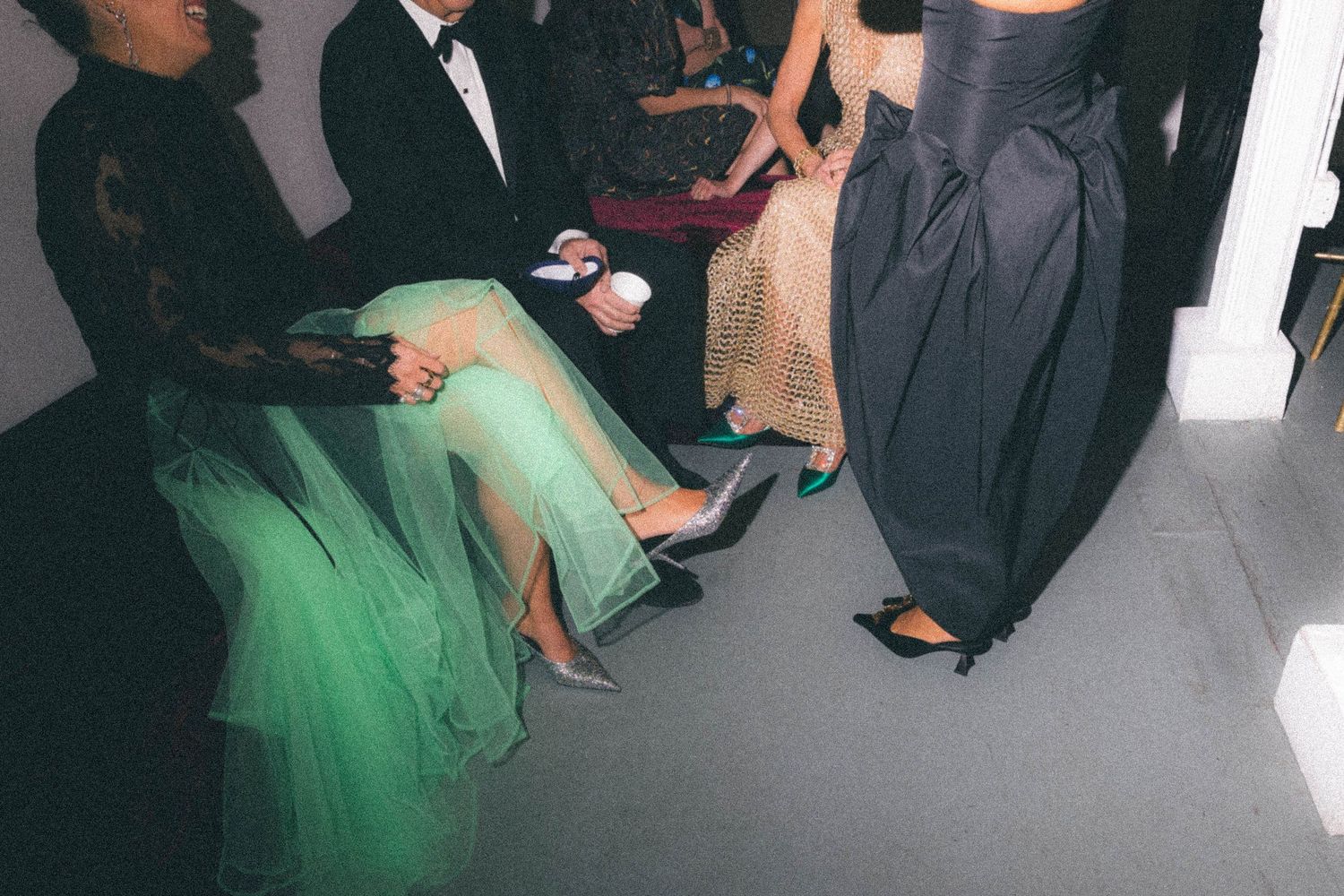 Guests in formal gowns seated and standing at wedding event showing green tulle and black dresses.
