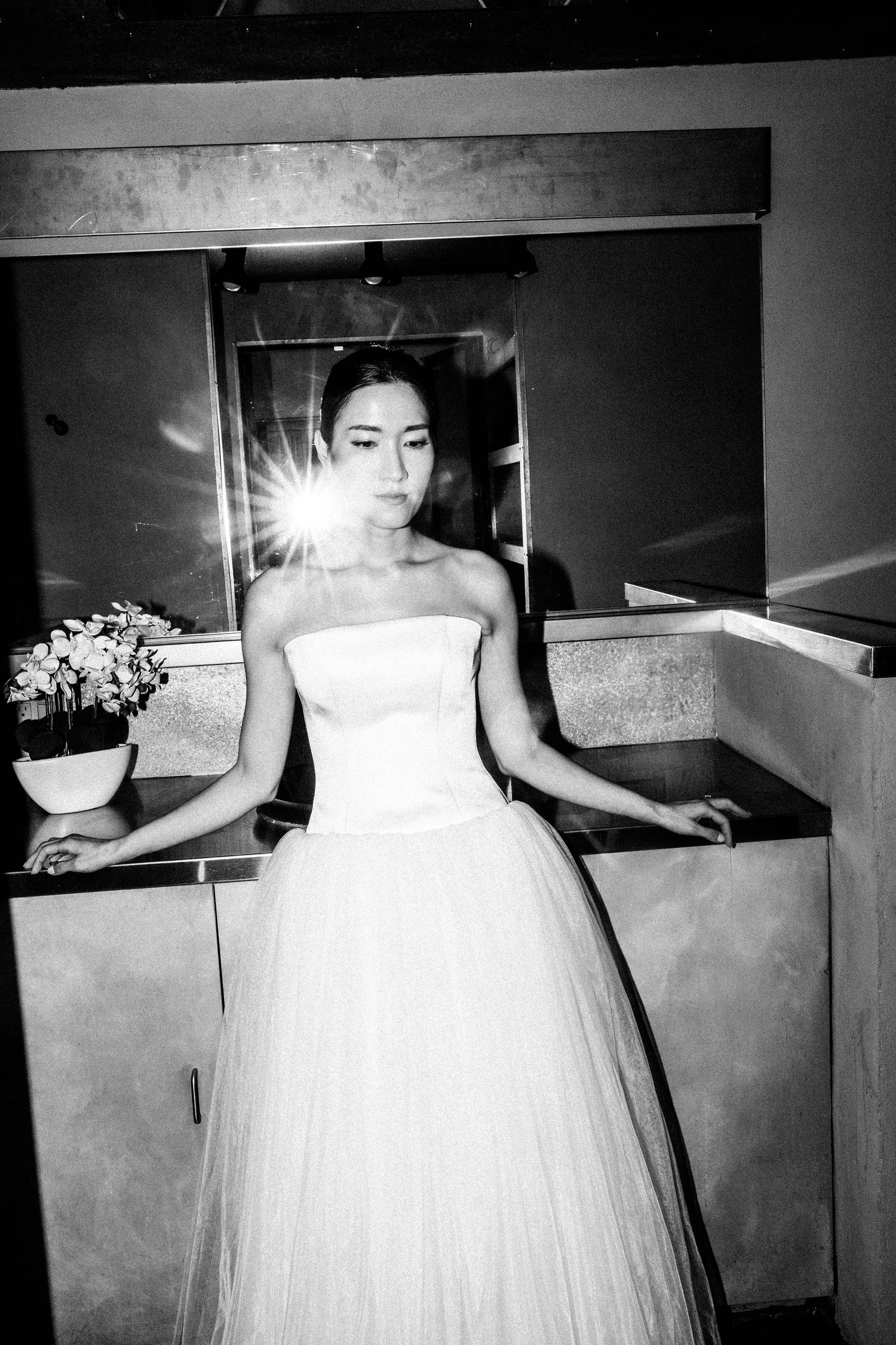 Bride in strapless white ball gown posing elegantly in black and white photo with mirror reflection.