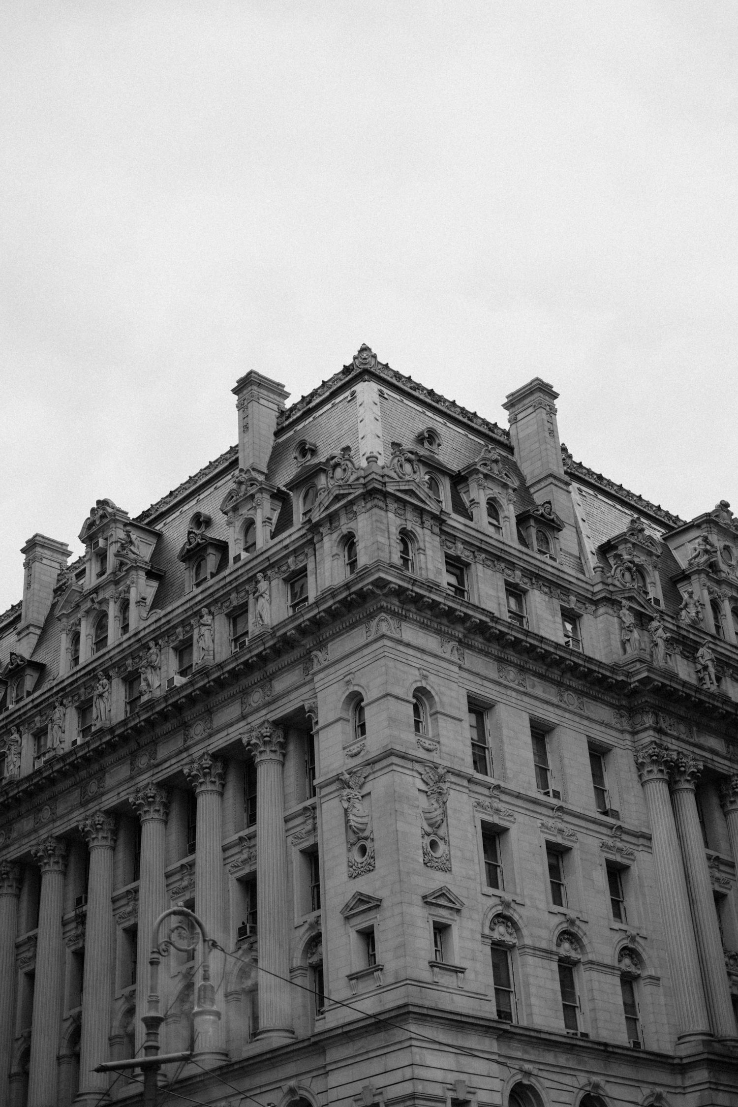Black and white architectural photo of ornate historic building corner against overcast sky.