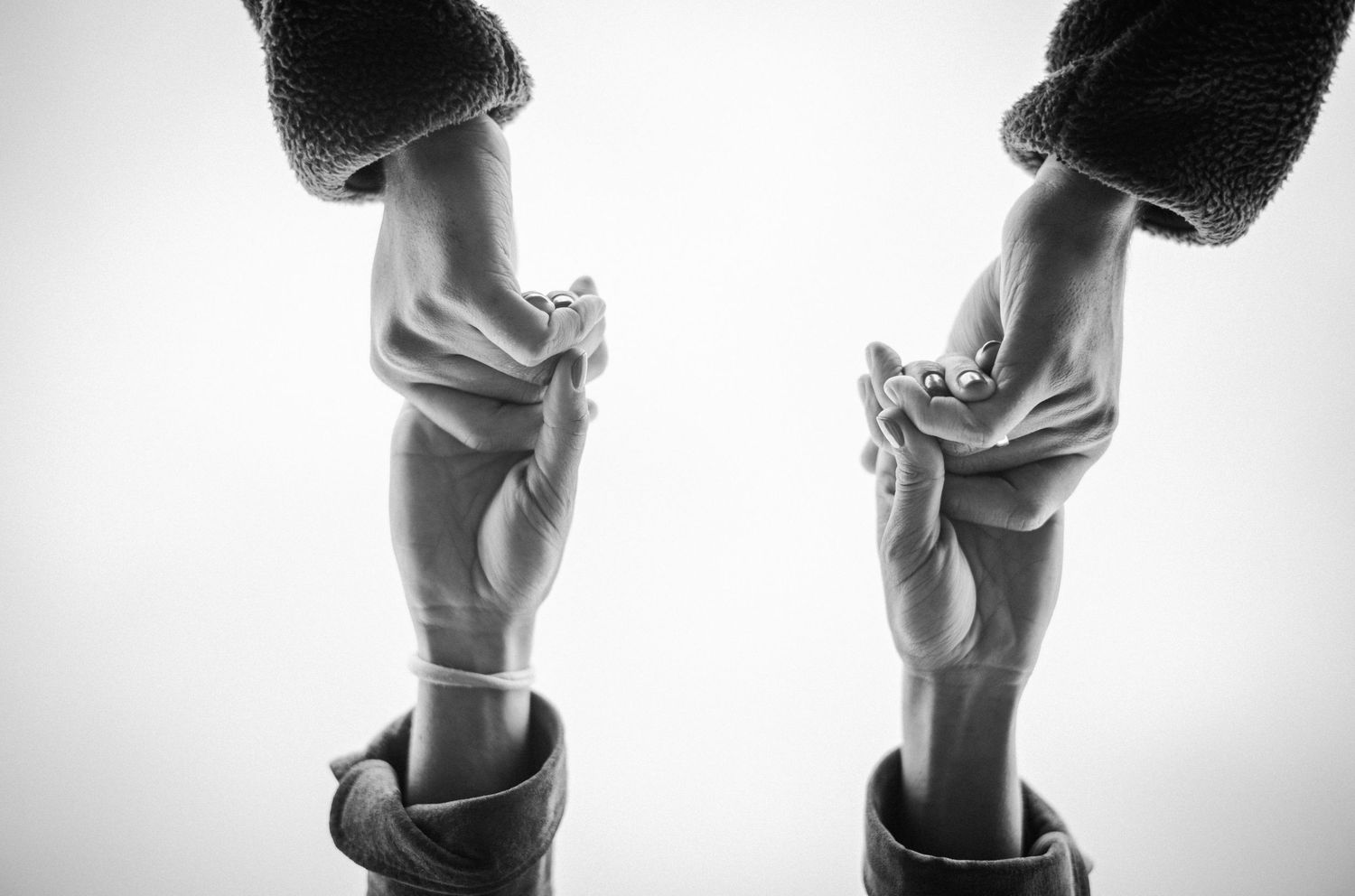 Black and white photo of two adults holding tiny baby feet, symbolizing love and new parenthood.Photography by The Y.K. Studio.