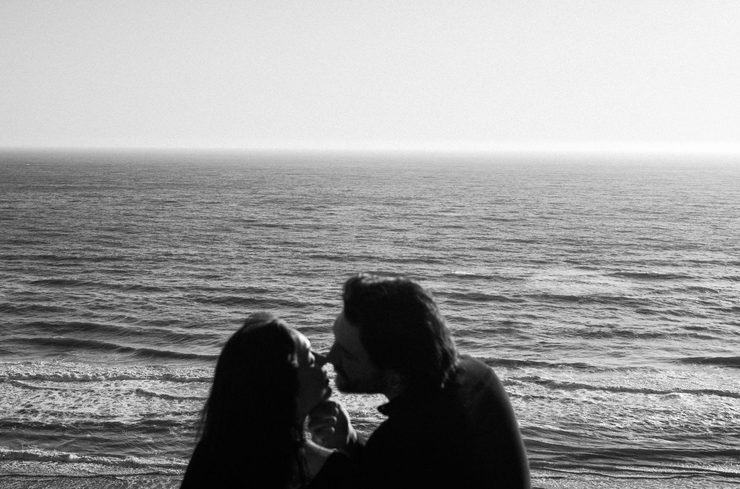 Romantic couple about to kiss with ocean horizon in black and white.