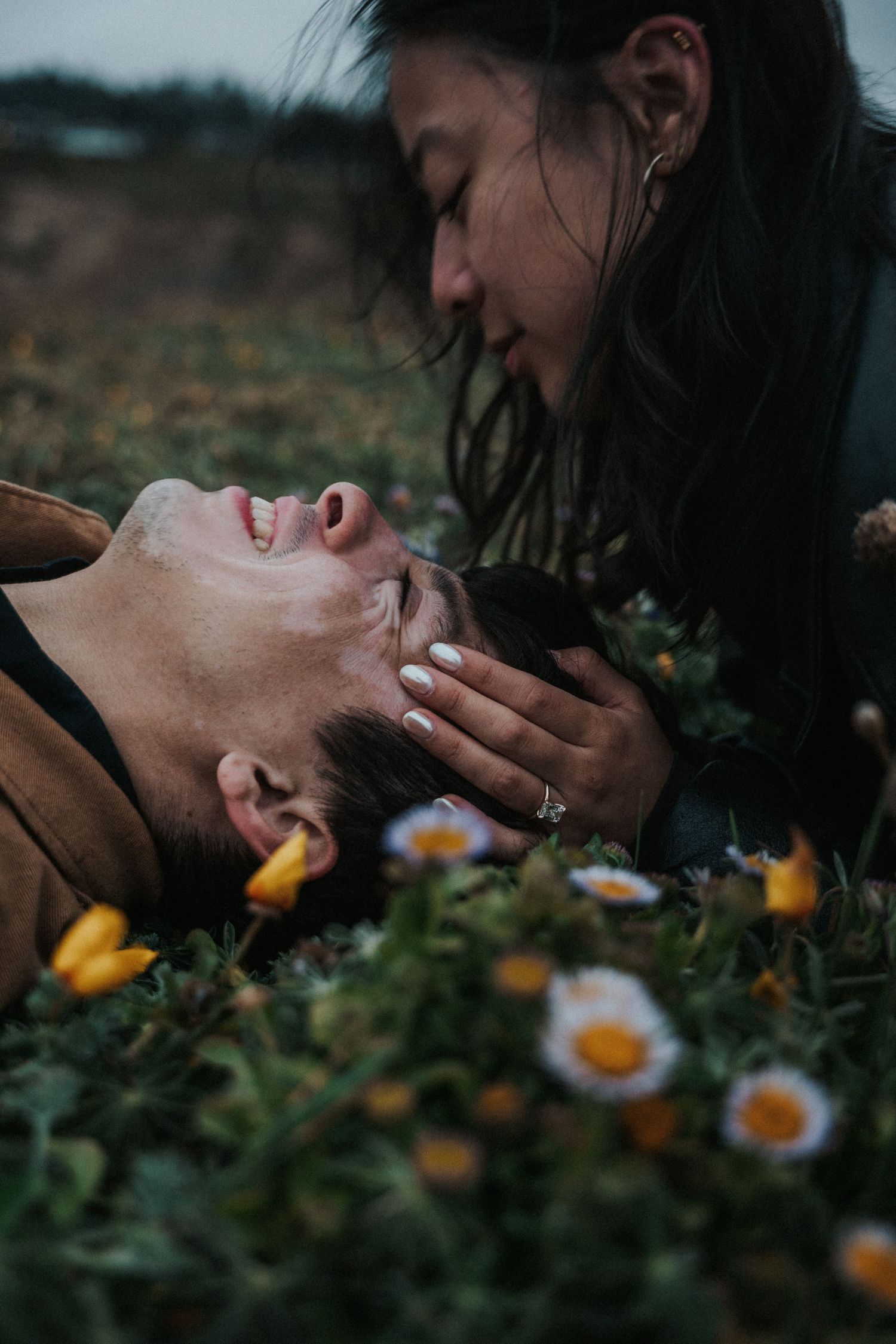 Couple sharing a romantic moment in a field of daisies and yellow wildflowers.