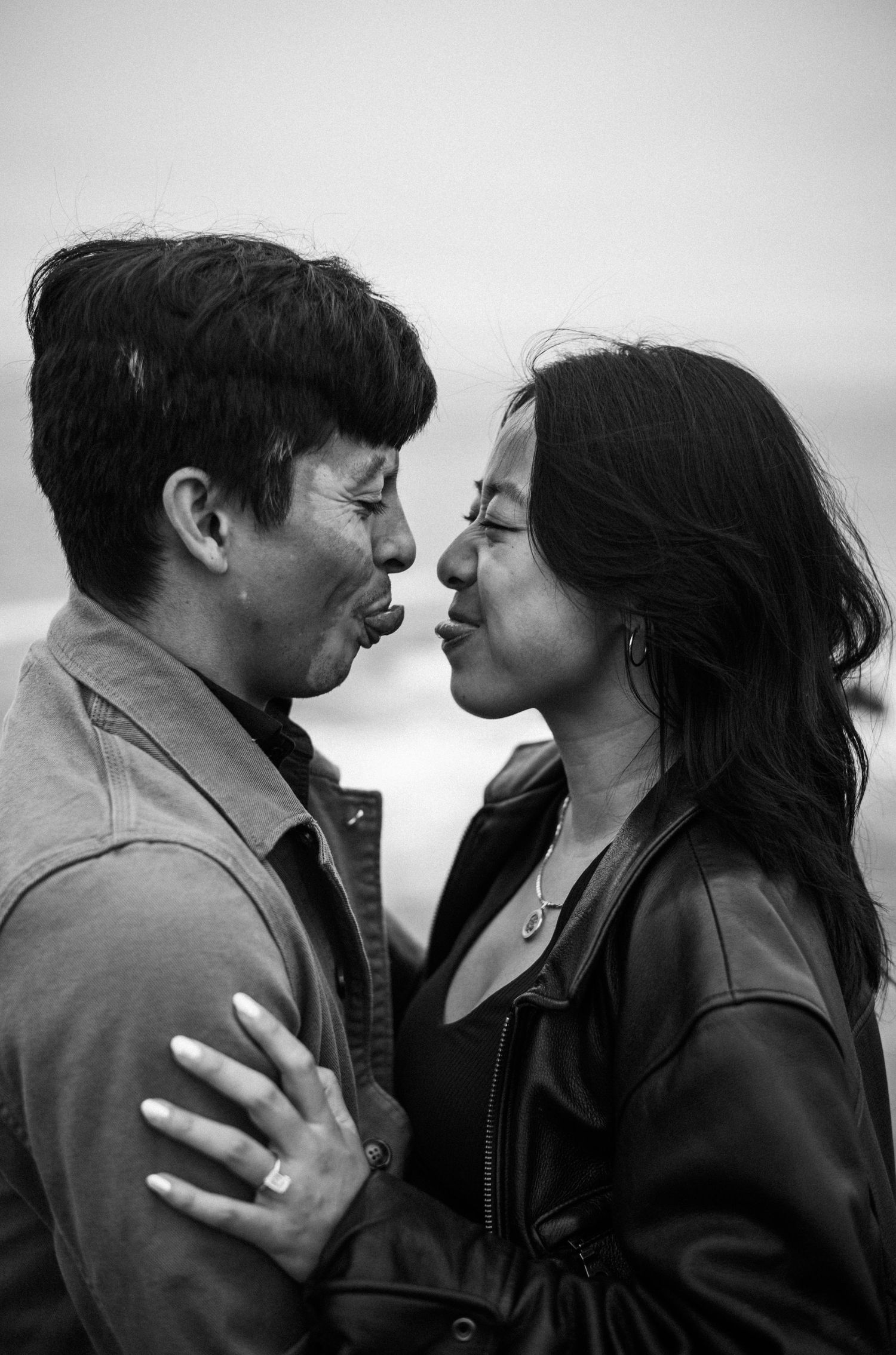 Black and white photo of a couple sharing an intimate moment, facing each other closely outdoors.