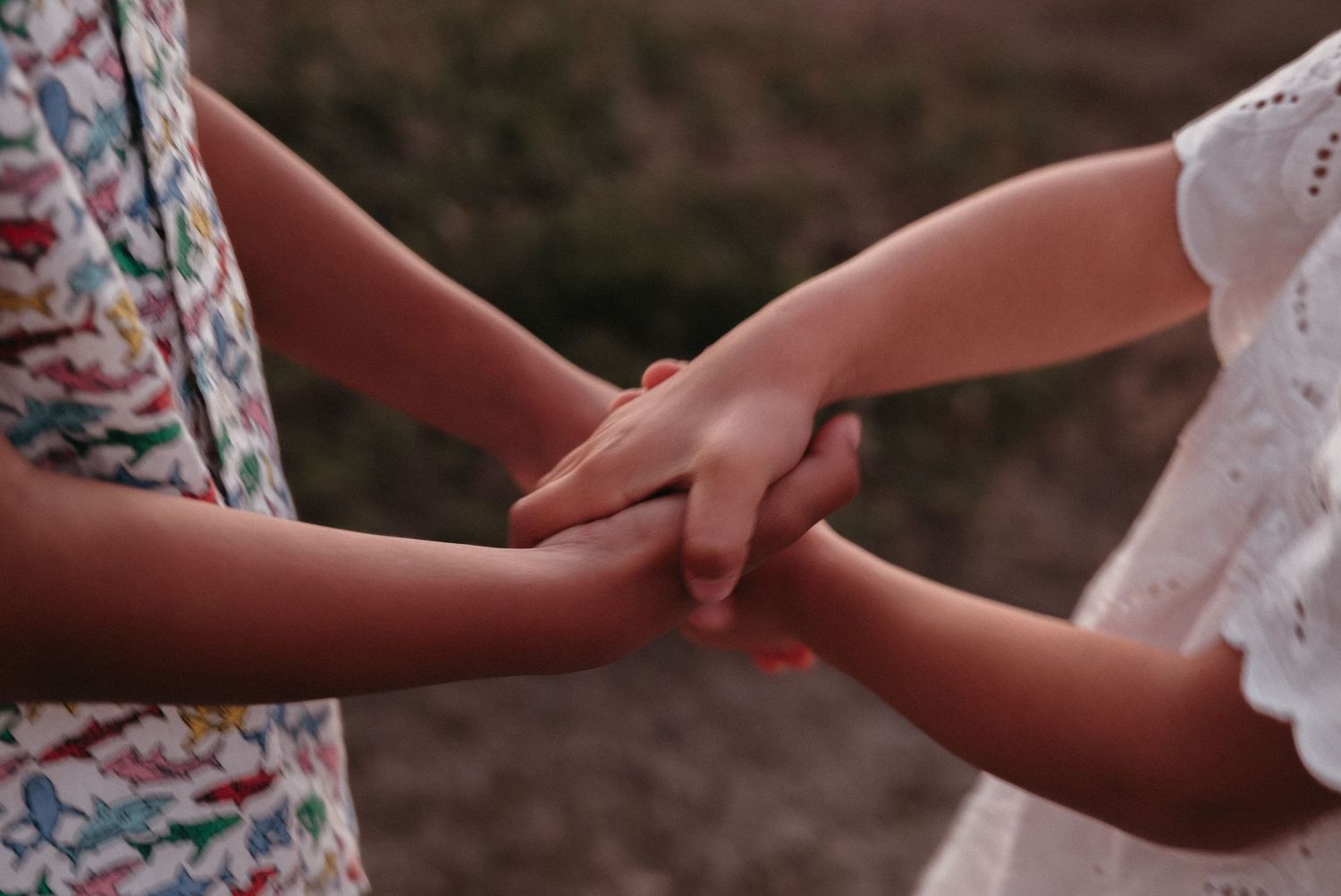 Two children holding hands together outdoors, symbolizing friendship and childhood bonding.