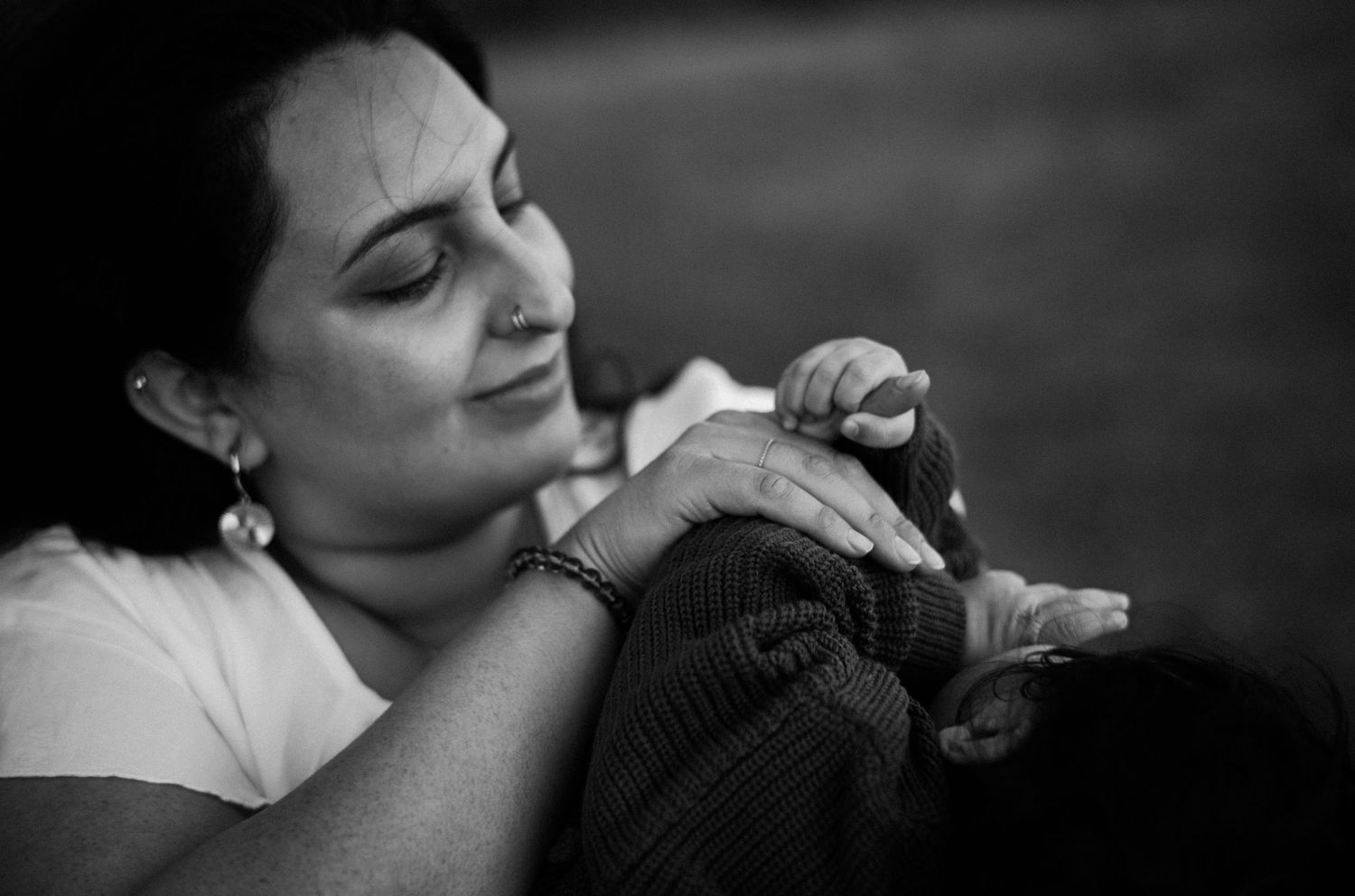 Black and white photo of a woman tenderly holding a newborn baby in her arms.