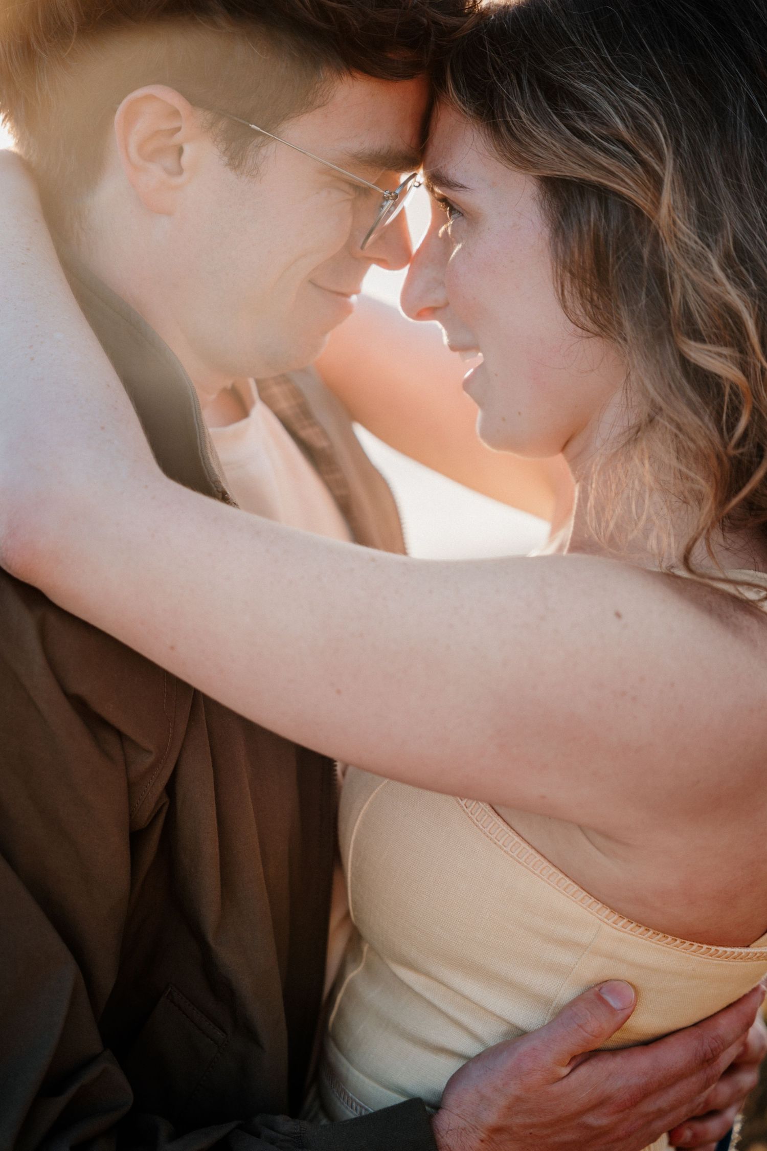 Couple sharing an intimate moment with foreheads touching in warm golden sunlight.