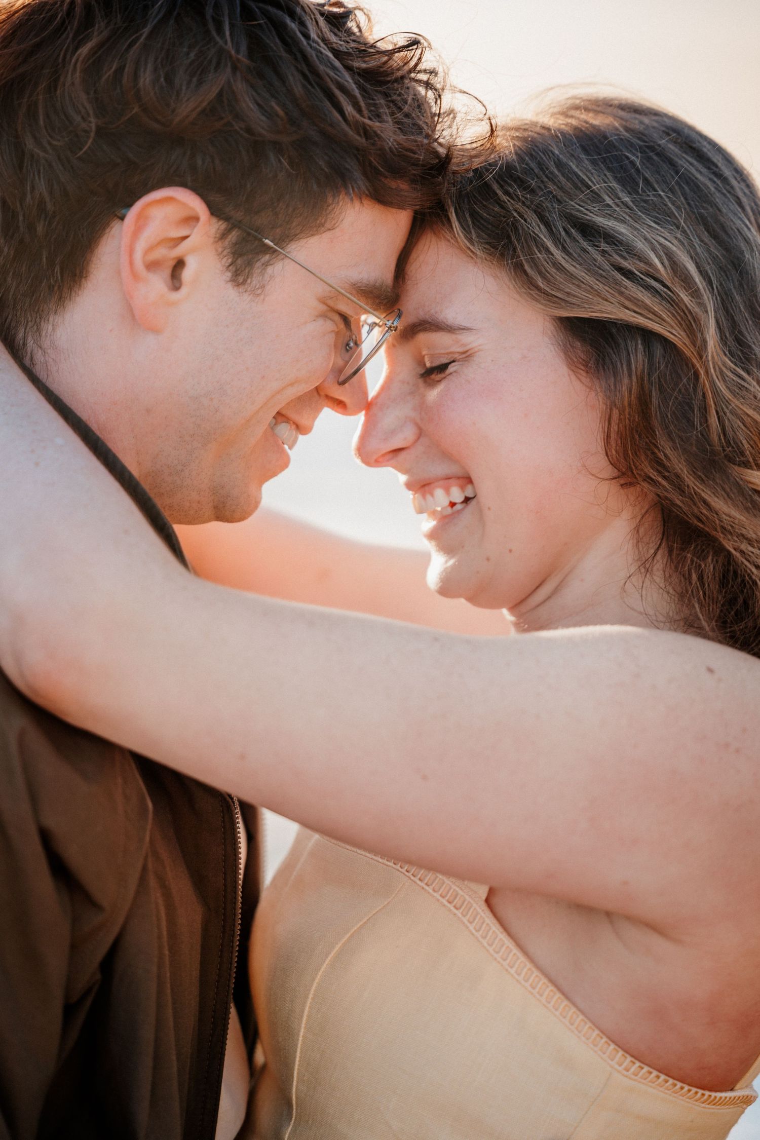Happy couple smiling with foreheads touching in a warm golden sunset light. Photography by The Y.K. Studio.