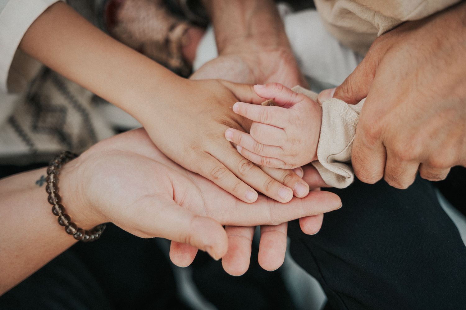 Family hands stacked together, including a newborn baby hand, symbolizing love, unity, and new parenthood.