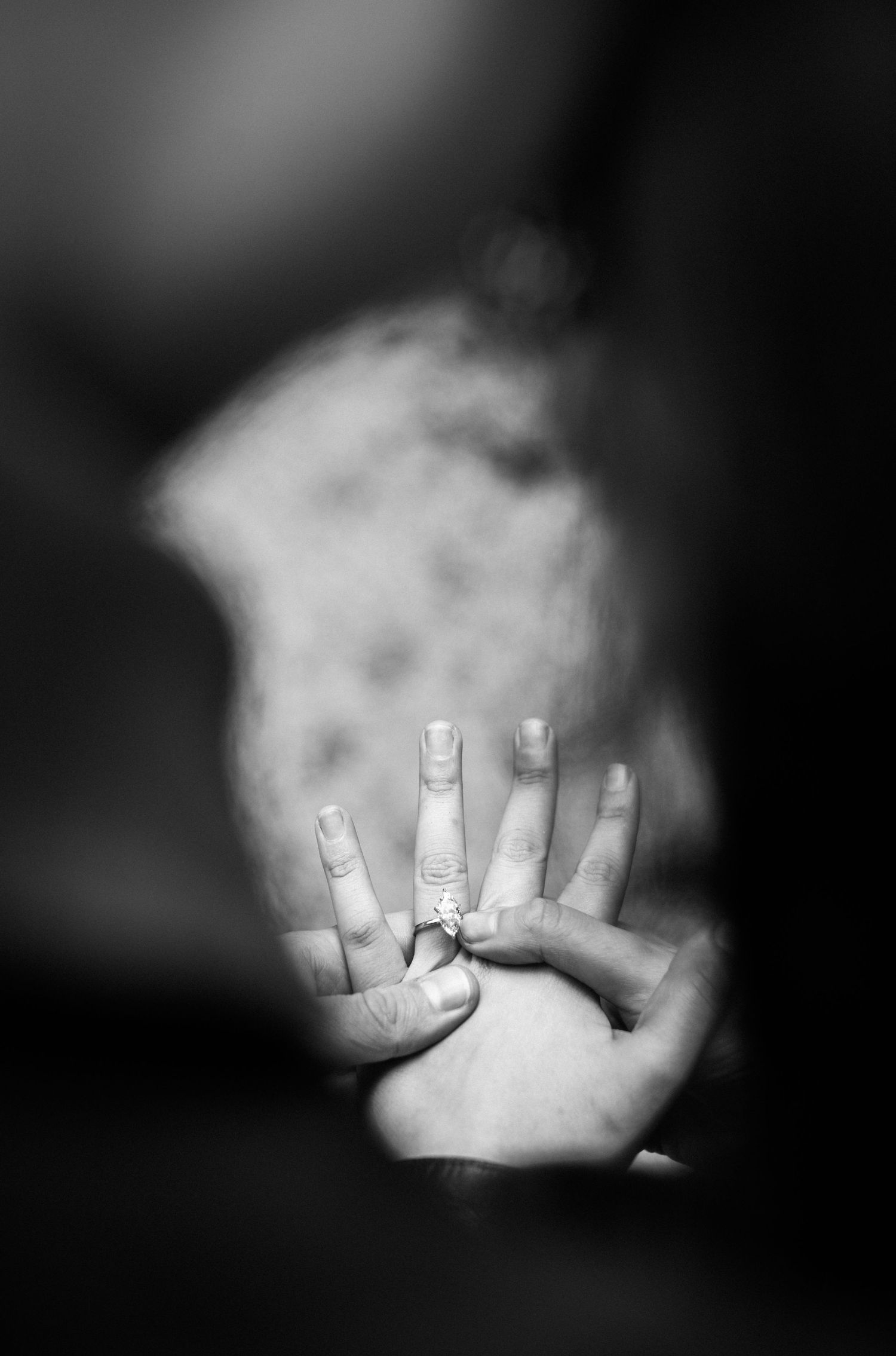Black and white close-up of hands holding showing an engagement ring.