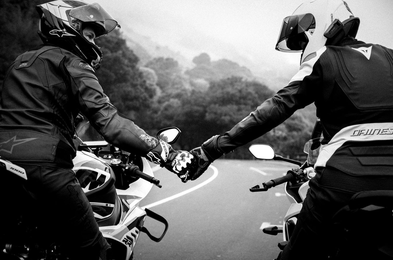 Couple on motorcycles holding hands with the Golden Gate Bridge in the background.
