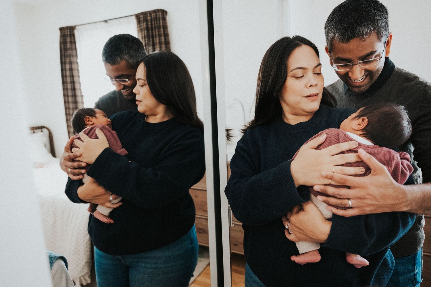 Couple in black sweaters tenderly holding newborn baby, reflected in mirror, capturing a precious family moment.
