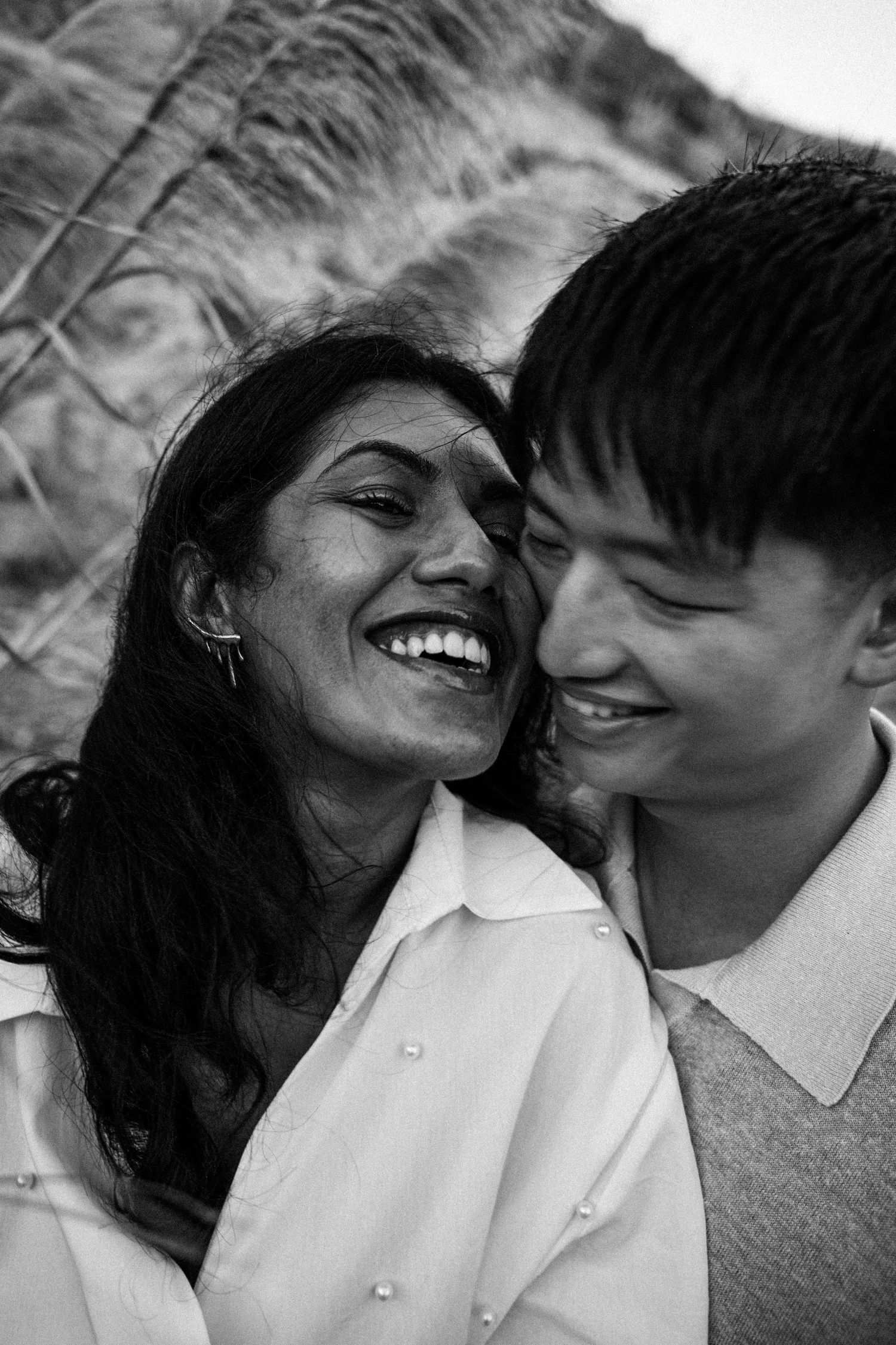 Black and white portrait of a joyful couple smiling and laughing together outdoors in natural light.