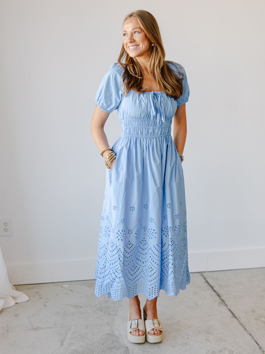 Woman wearing a light blue eyelet midi dress with smocked waist and puff sleeves, paired with white platform sandals.