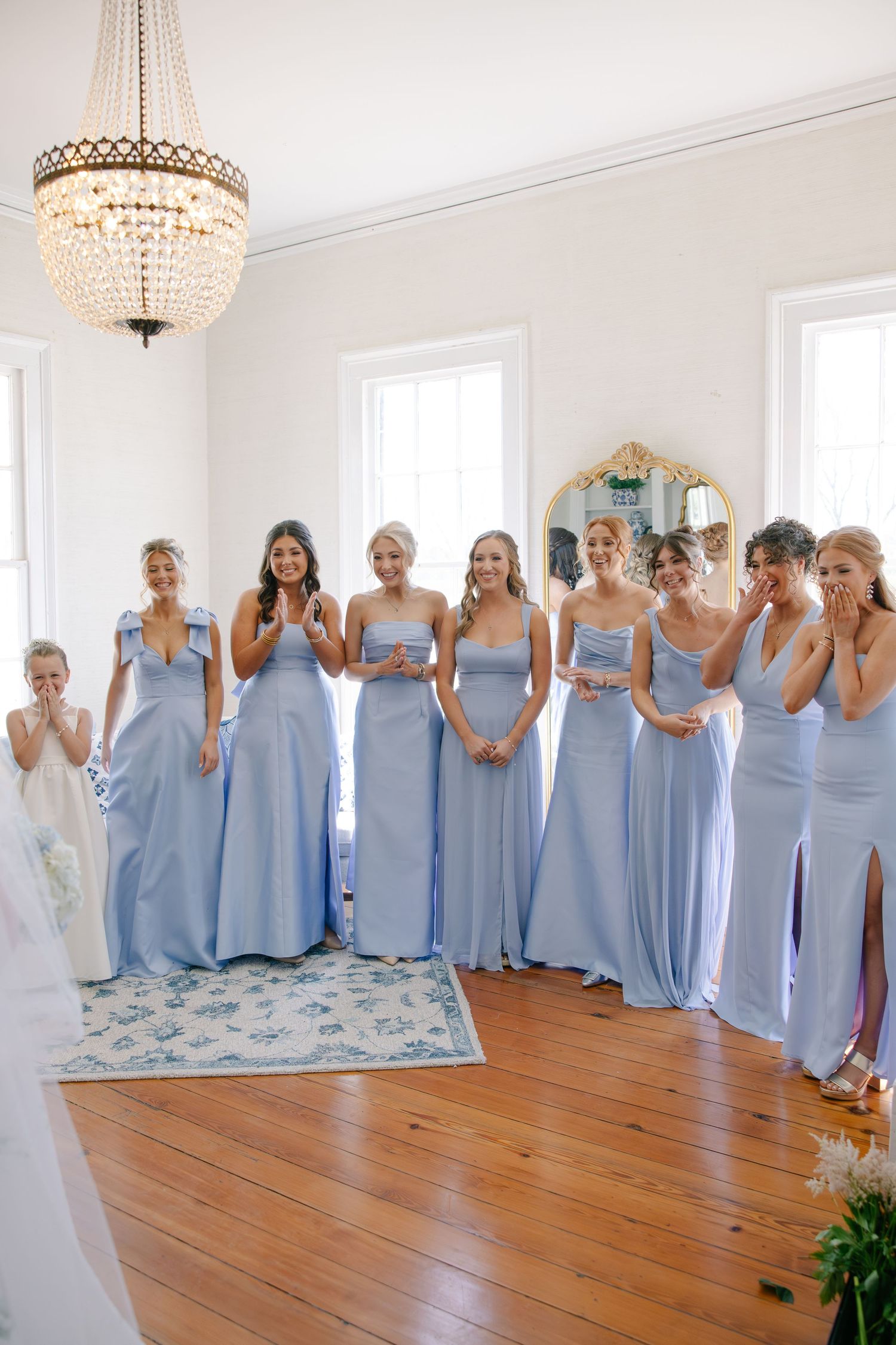 Bridesmaids in blue gowns reacting emotionally to bride's first look reveal.