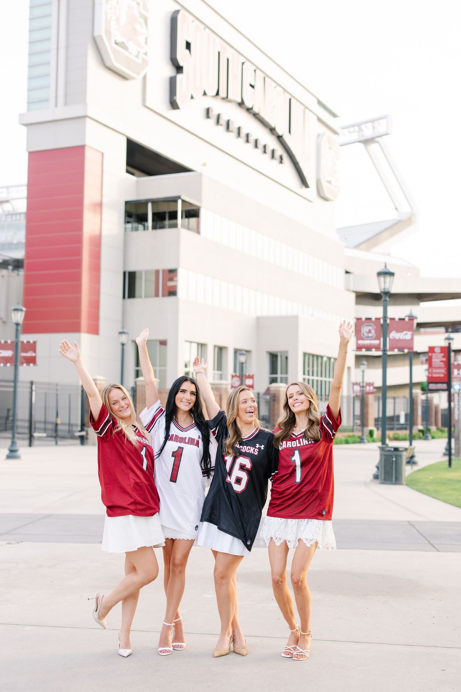Four women in South Carolina Gamecocks jerseys cheering outside Williams-Brice Stadium.