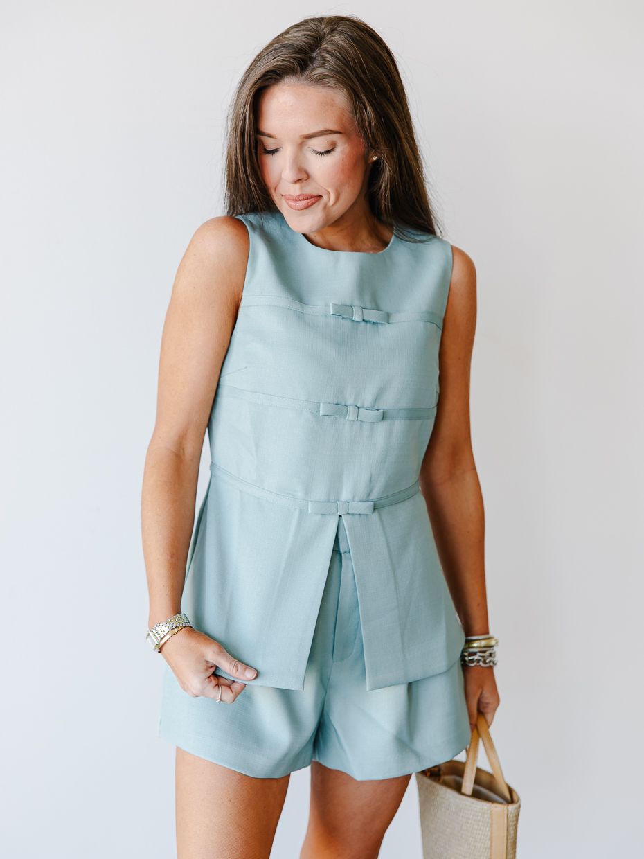 Woman modeling a sage green sleeveless bow-detail top and matching shorts coordinated set.