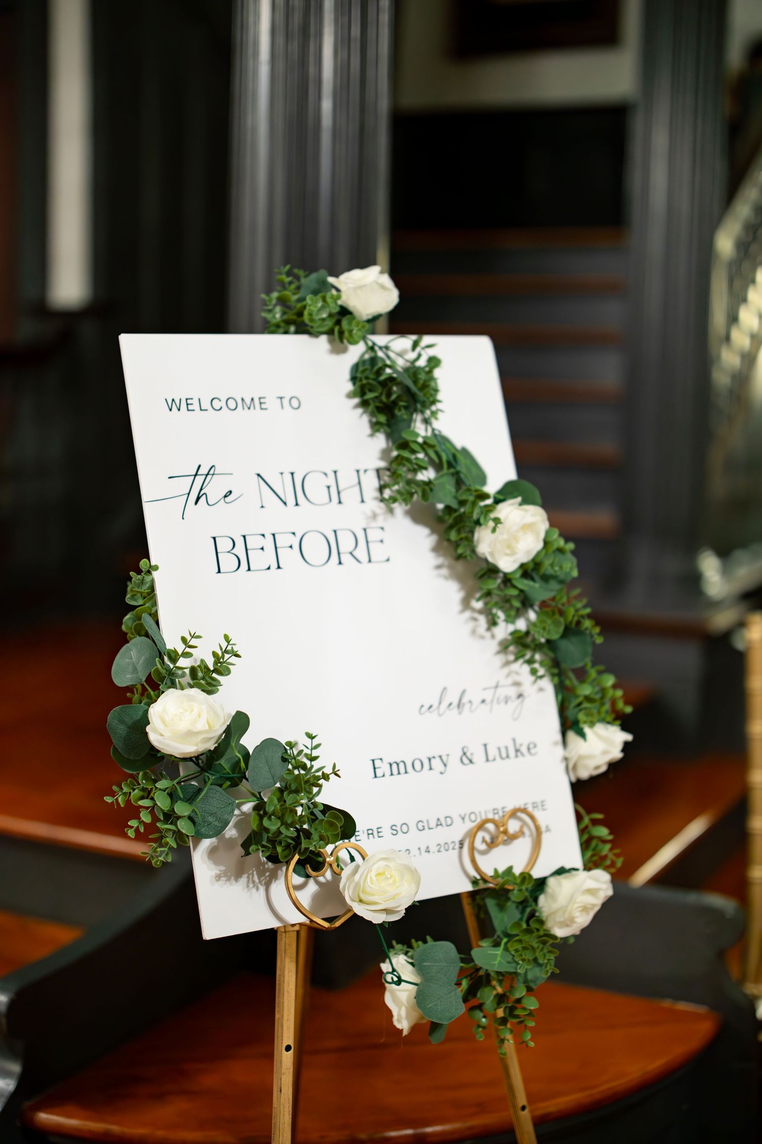 Elegant welcome sign for The Night Before rehearsal dinner celebration for Emory and Luke with floral garland.