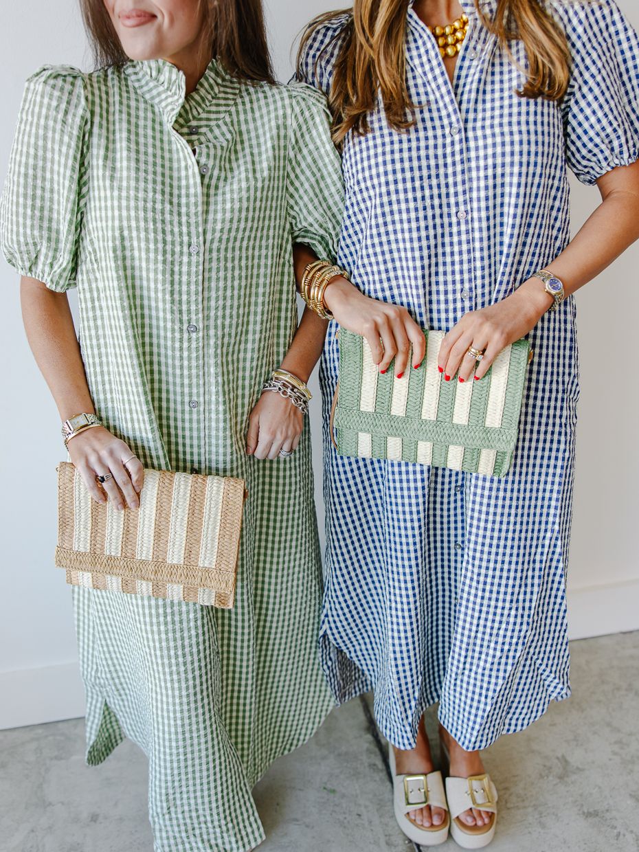 Two women in green and blue gingham midi shirtdresses holding striped woven clutch bags.