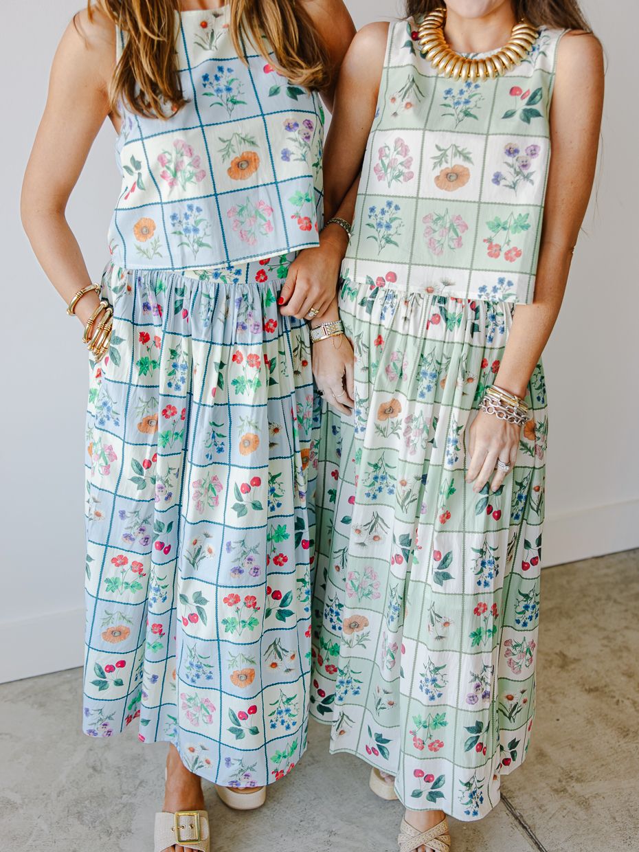 Two women wearing matching floral grid print sleeveless crop top and maxi skirt sets in mint green.