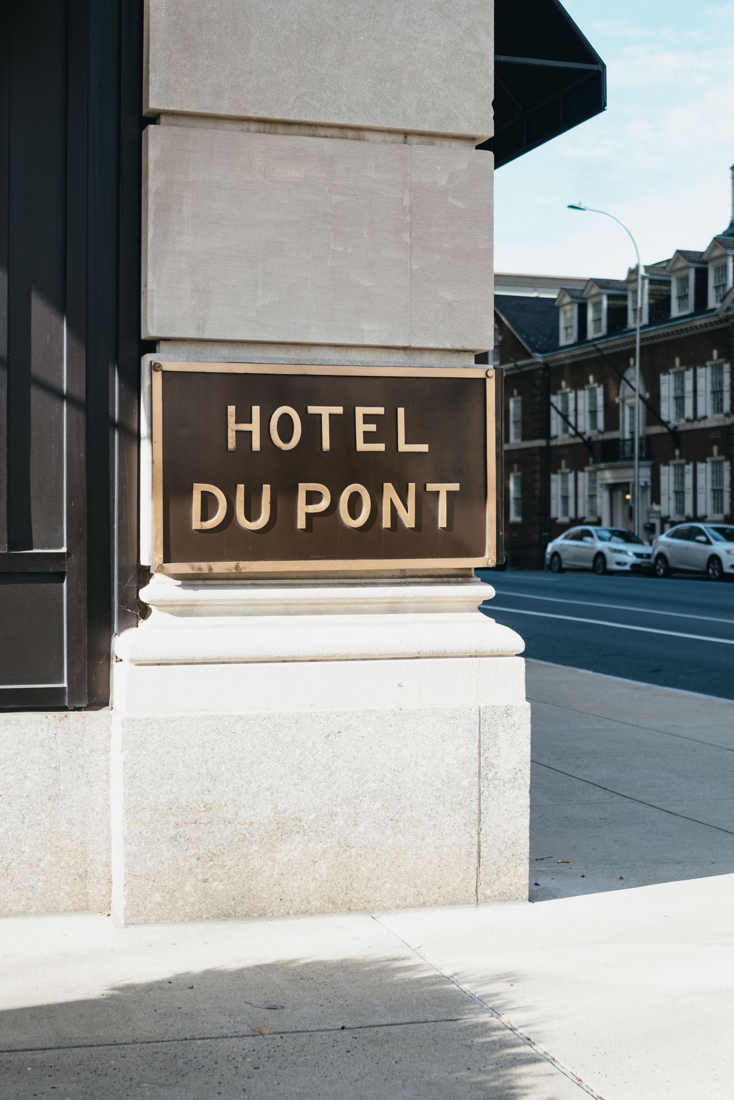 Hotel Du Pont sign on marble exterior column with street view in background Hotel DuPont wedding Philadelphia photographer