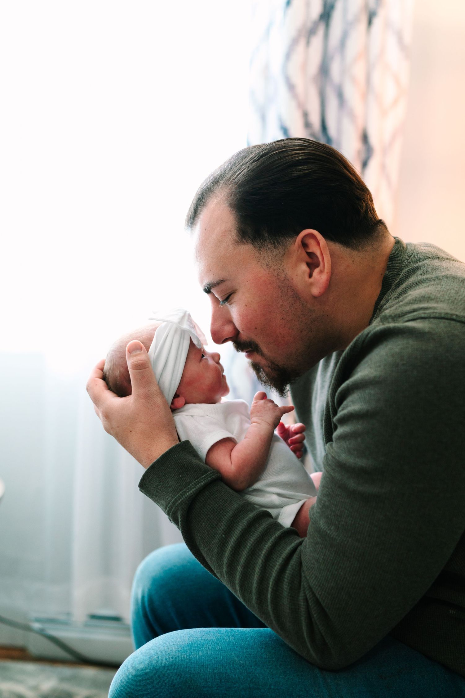 A father tenderly holds his newborn baby close, touching foreheads in a heartwarming bonding moment.