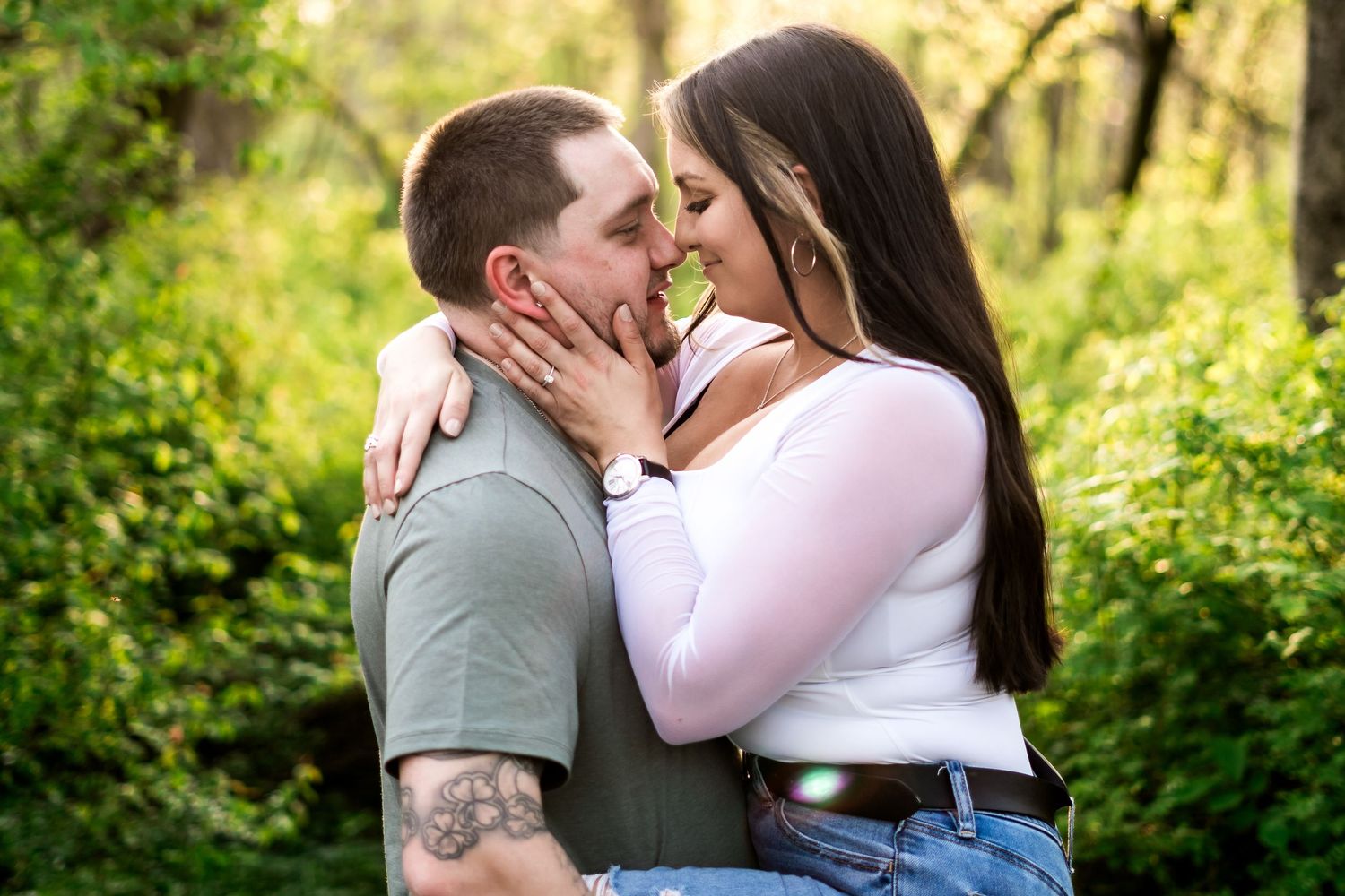 philly wedding photographer Couple sharing a romantic almost-kiss outdoors, surrounded by lush green trees in a nature setting.