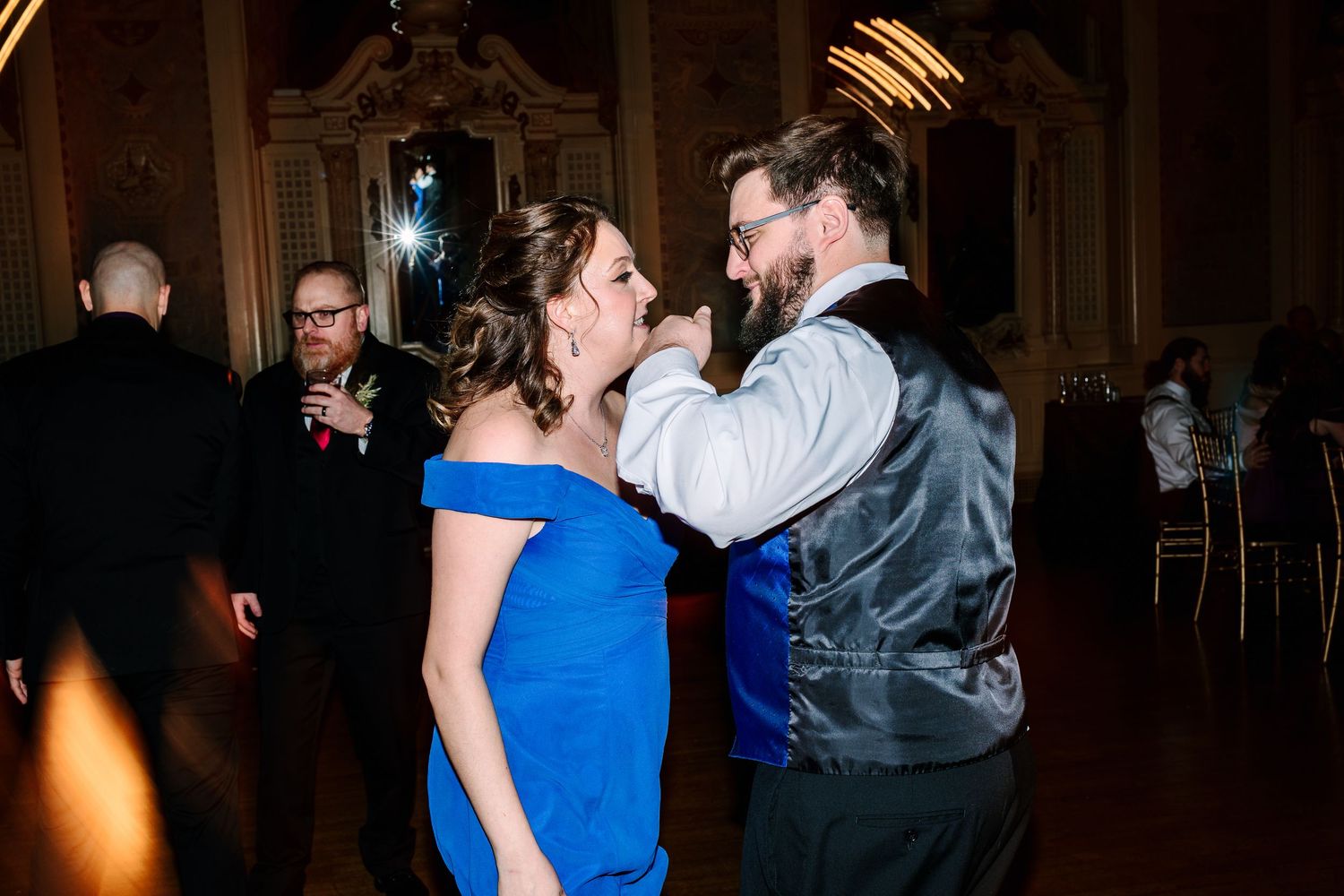 Couple sharing a romantic dance at a wedding reception in an elegant ballroom, woman in blue dress.