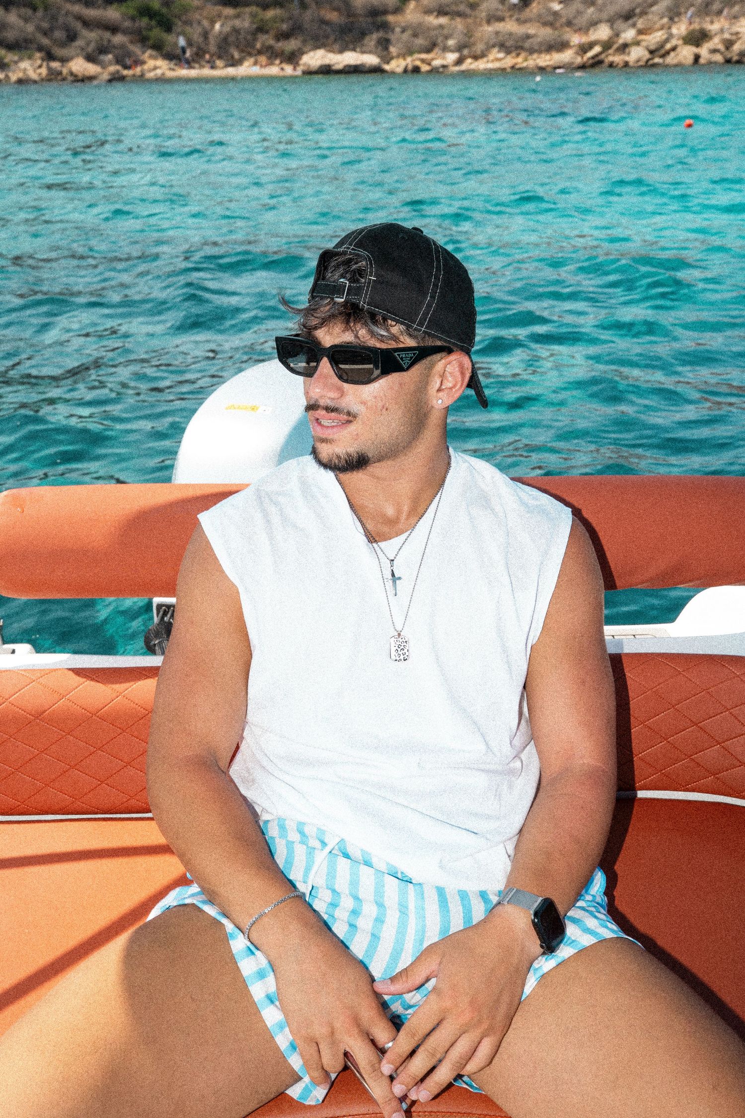 Young man in white tank top and striped shorts sitting on a boat.

lifestyle, portrait
