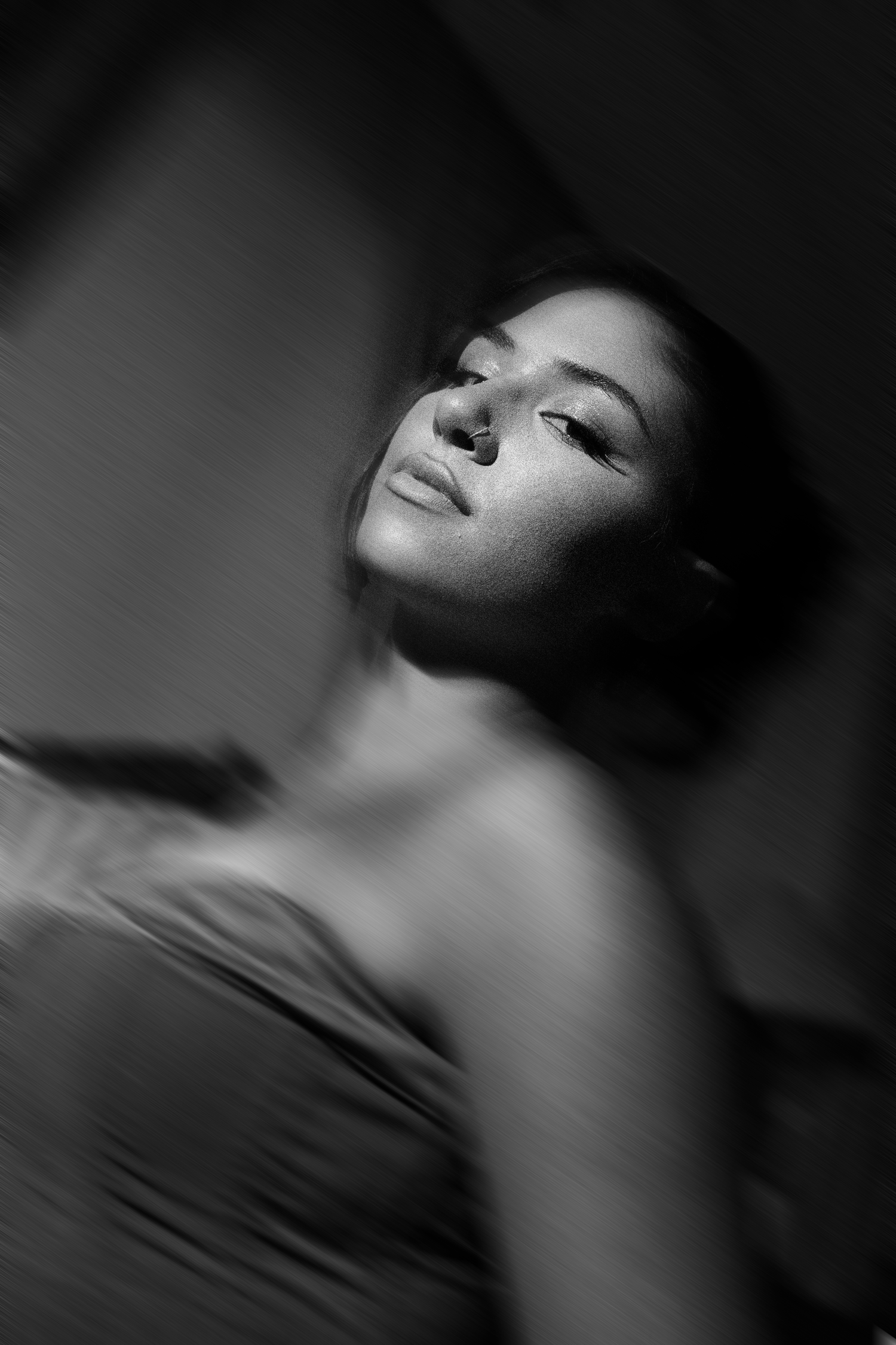 Black and white portrait of a woman with closed eyes in dramatic lighting.

portrait